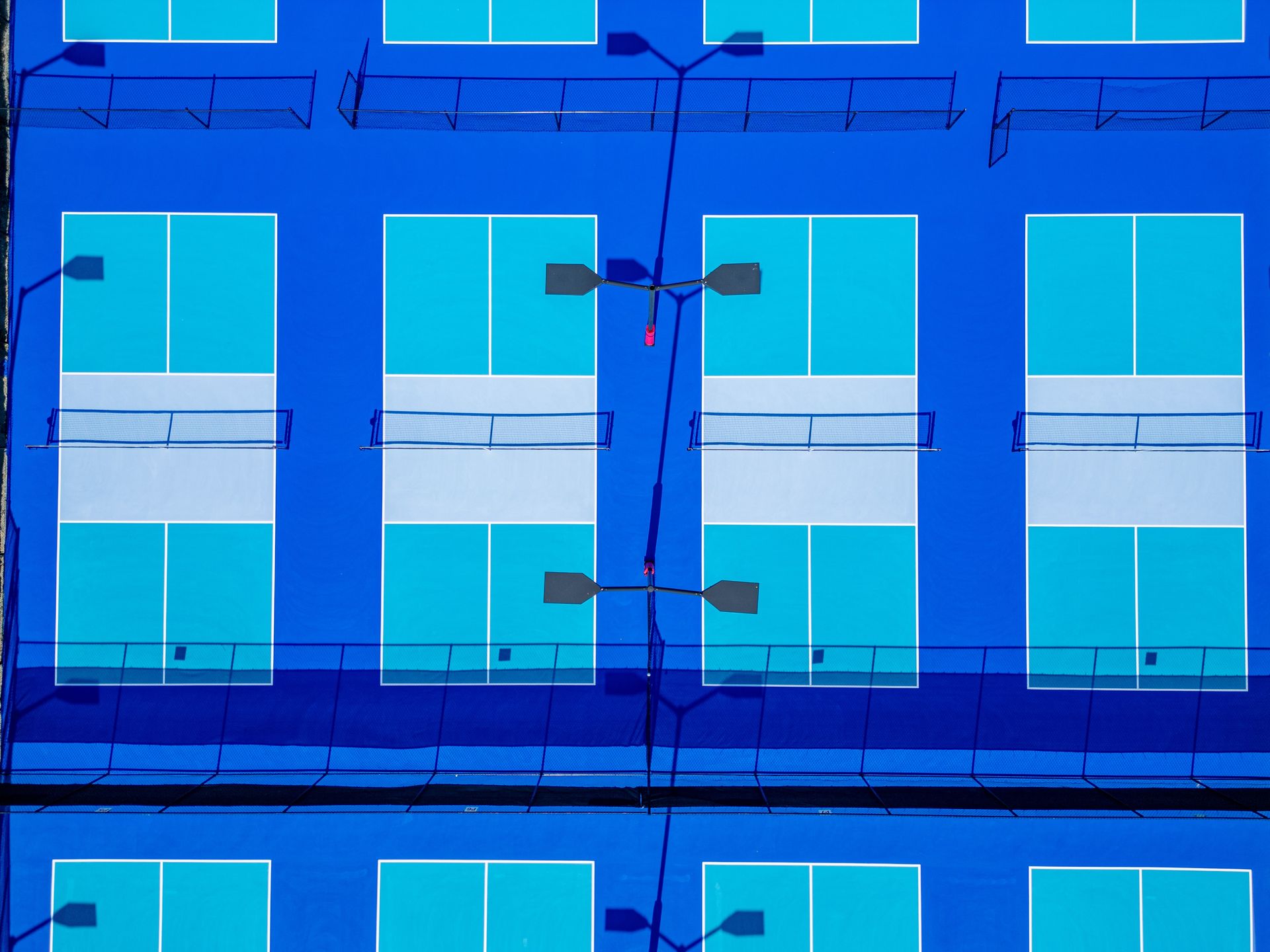 Blue apartment building facade with rows of turquoise windows and a few small balconies.