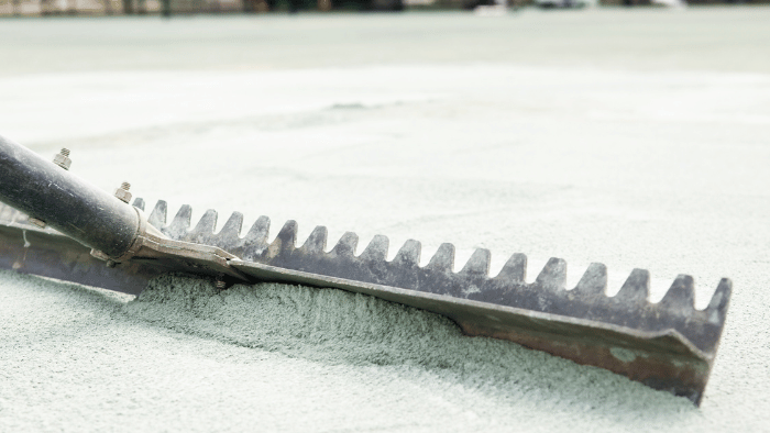 Close-up of a metal rake blade with teeth lying on a white surface