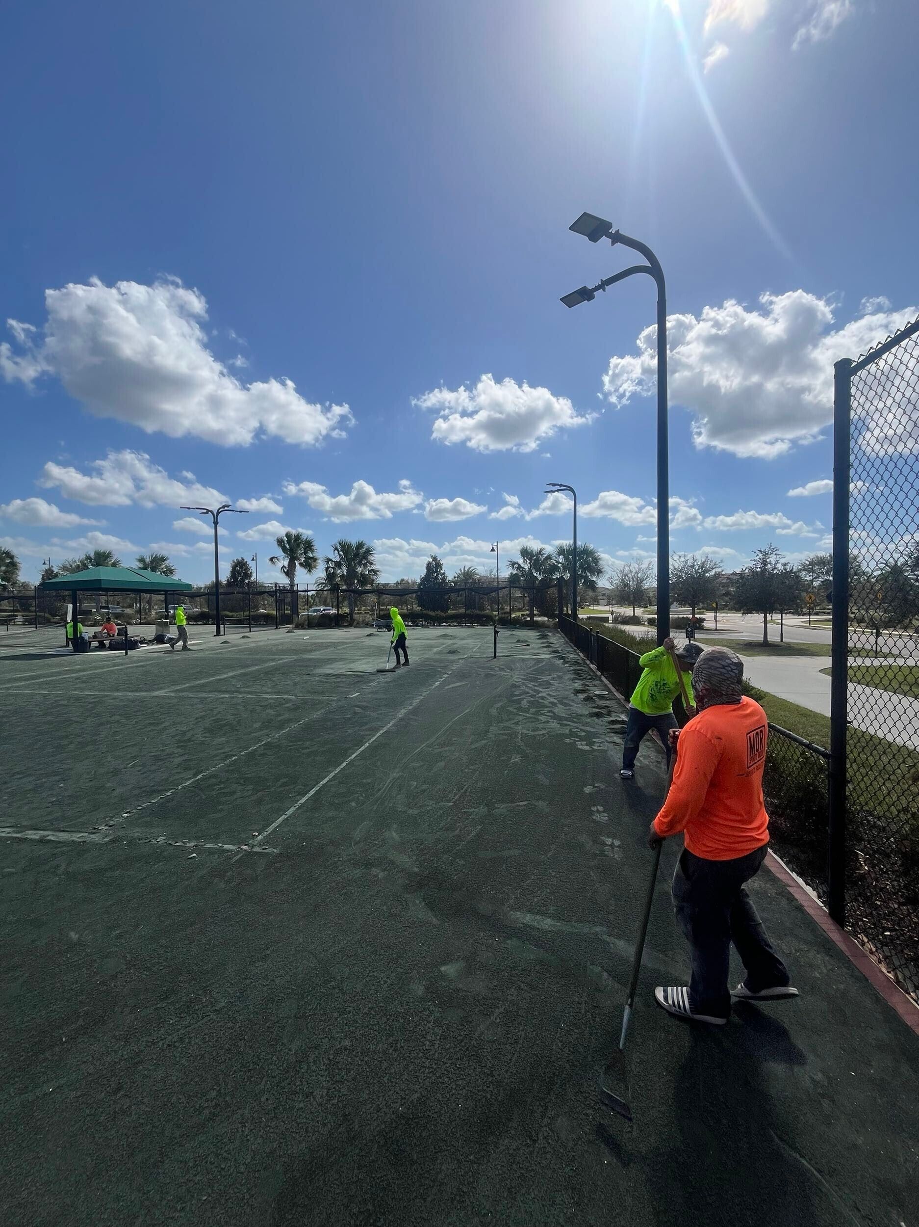 Outdoor soccer field with players in neon vests under a bright blue sky, seen from the sideline