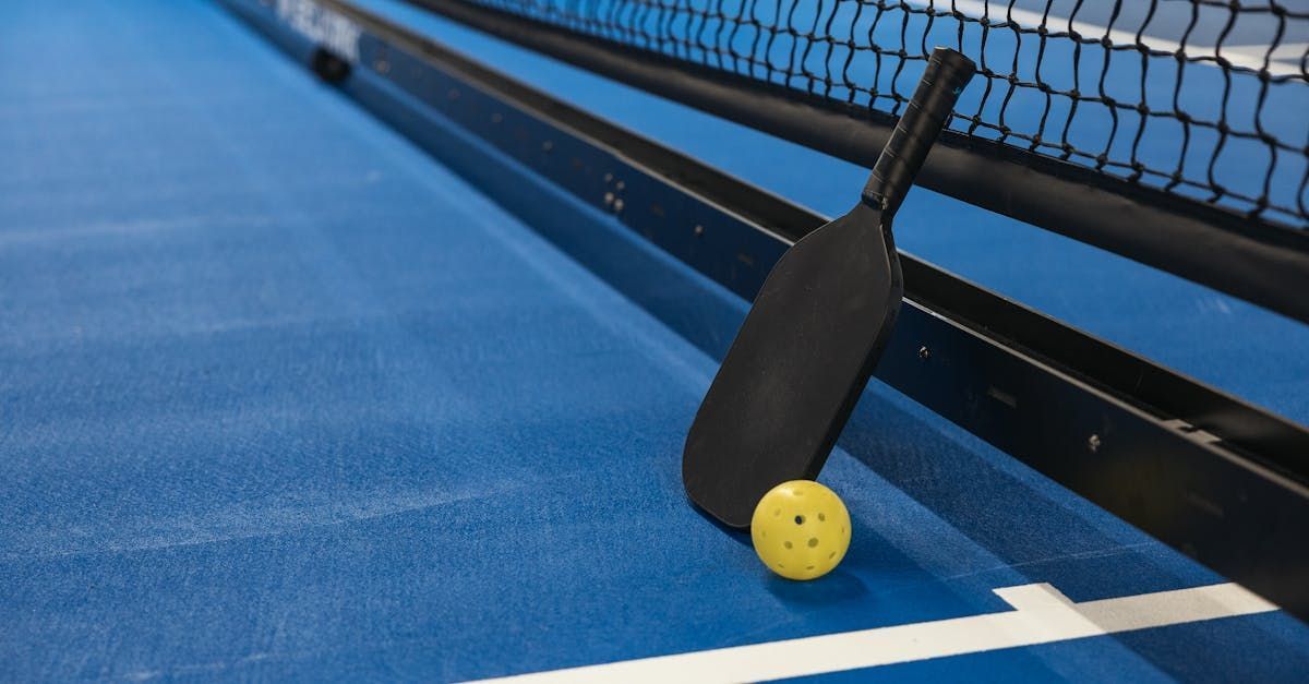 Pickleball paddle and ball on a blue court near the net