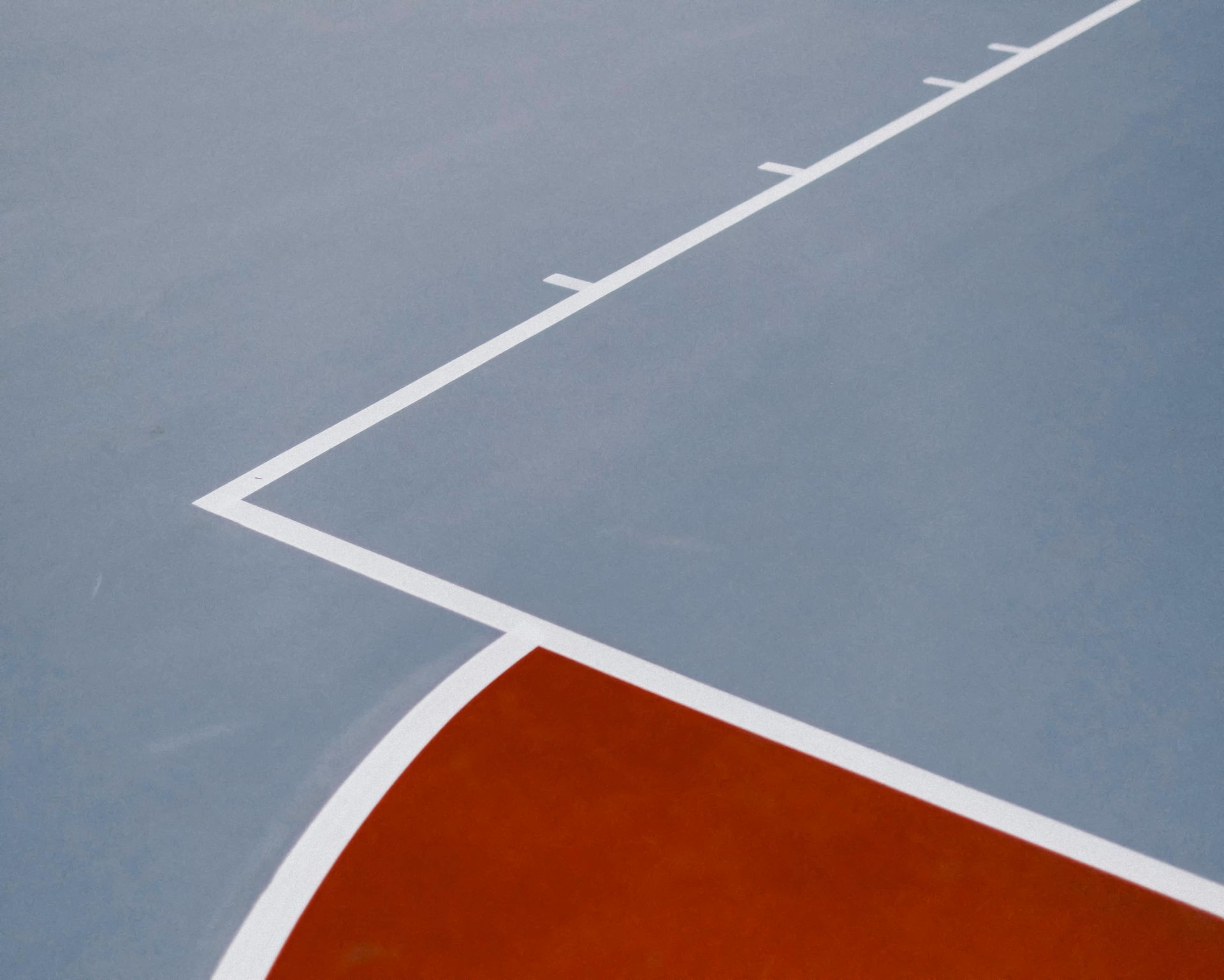 White court lines on a blue and orange court corner