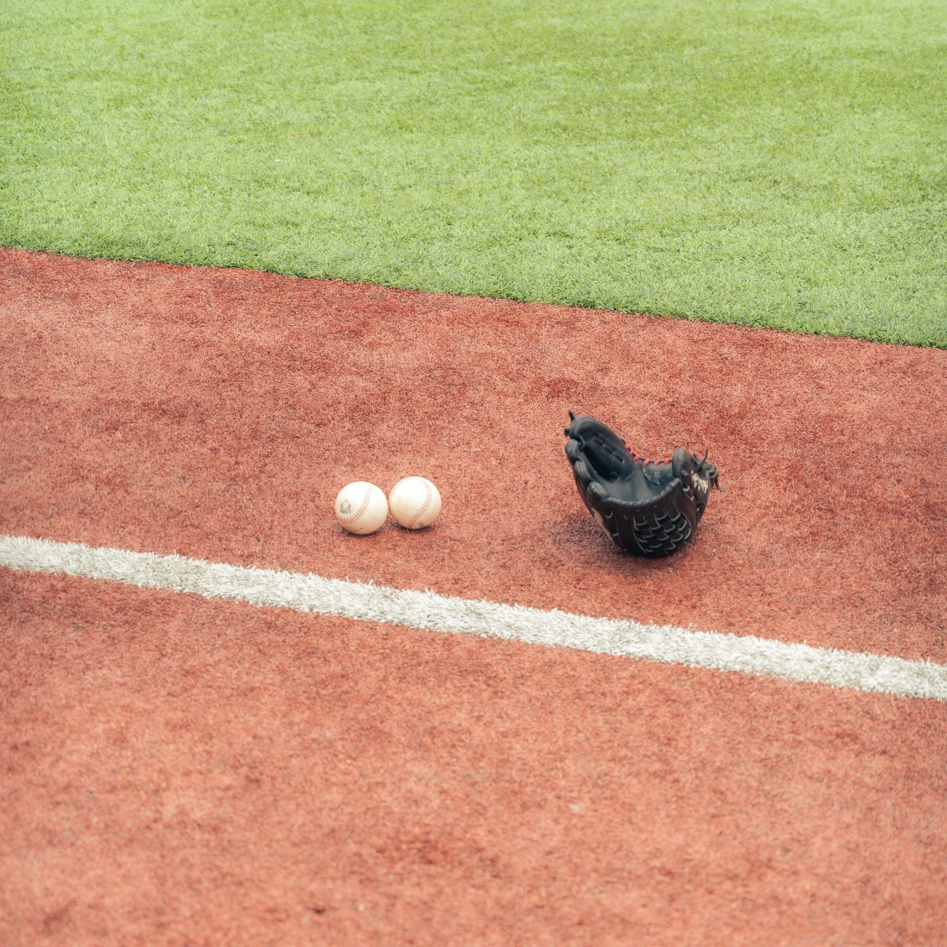 Empty baseball field with green grass, dirt infield, chain-link backstop, and cloudy sky