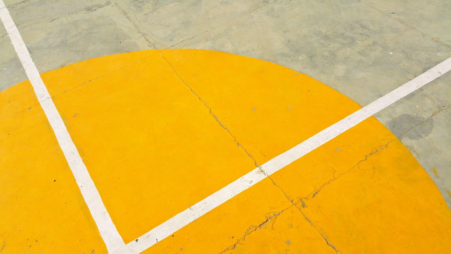 Yellow painted court circle with white boundary lines on a concrete surface