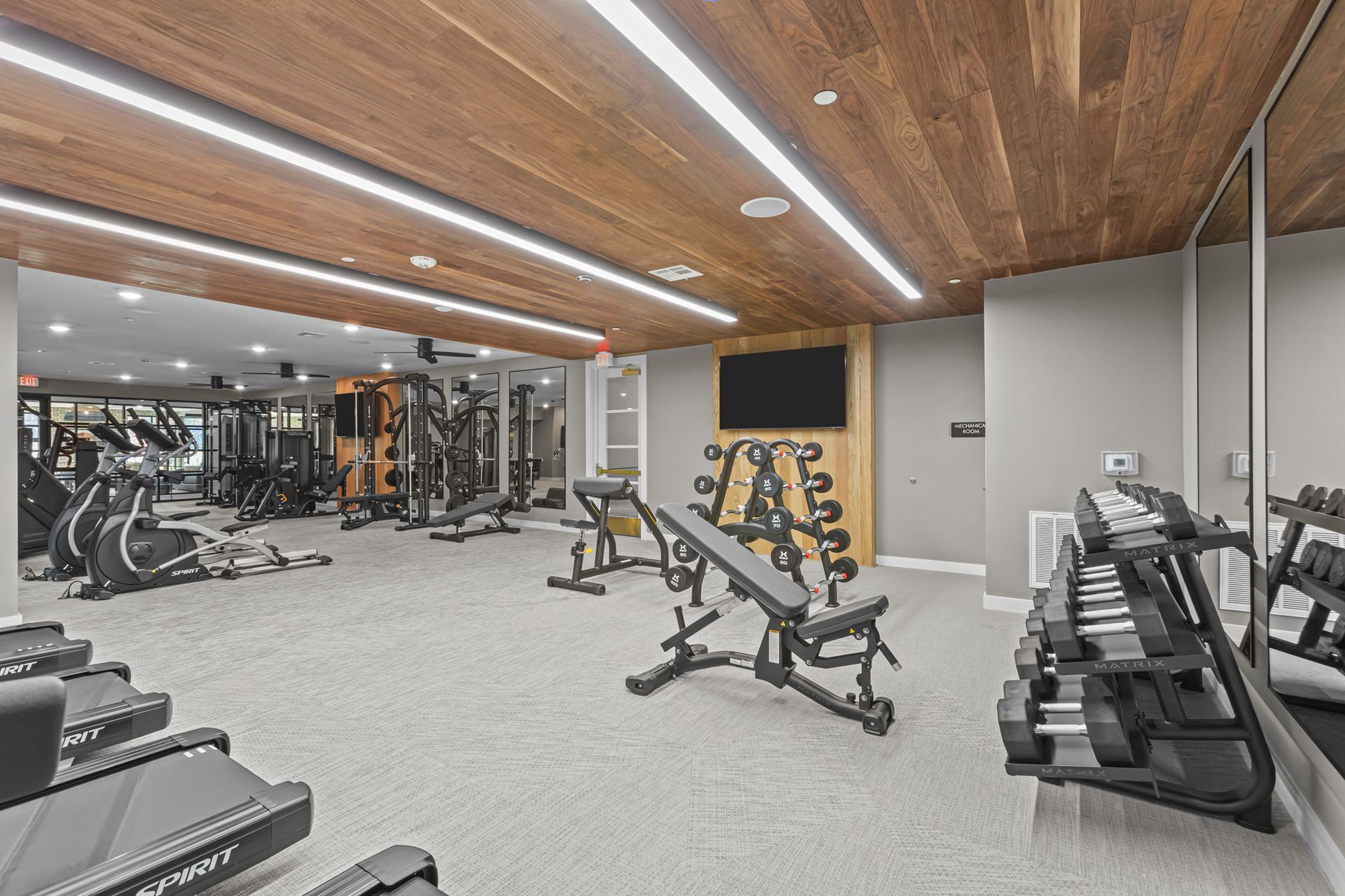 A large gym with a lot of equipment and a large mirror.