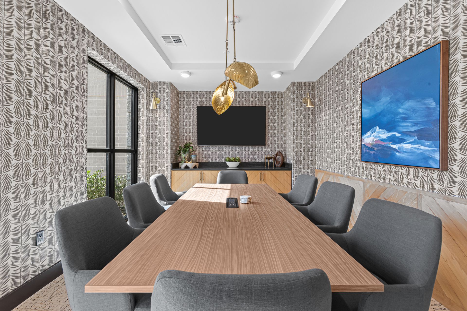 A conference room with a long table and chairs and a flat screen tv on the wall.