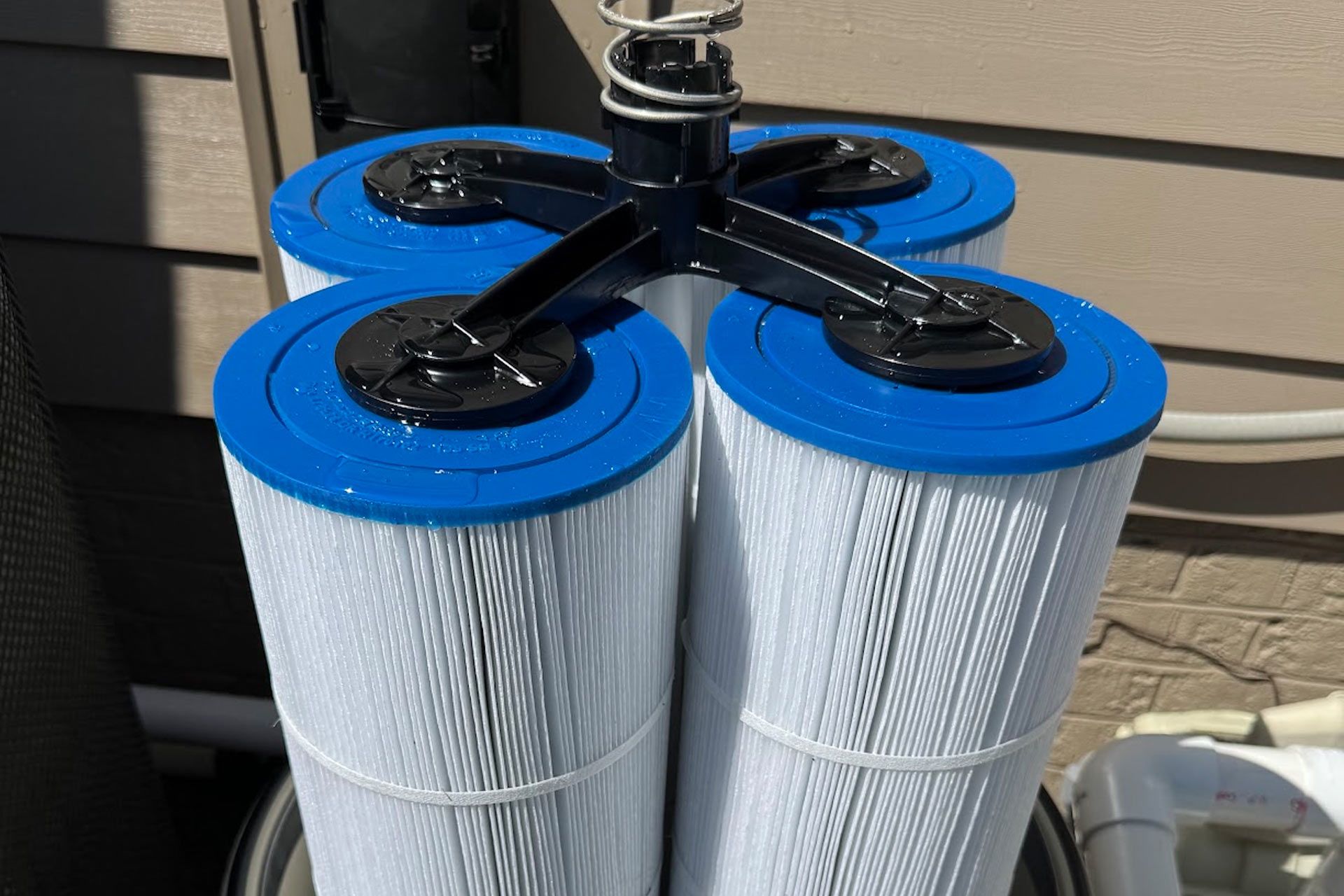 Four blue-and-white cylindrical filters strapped together with black tubing outdoors