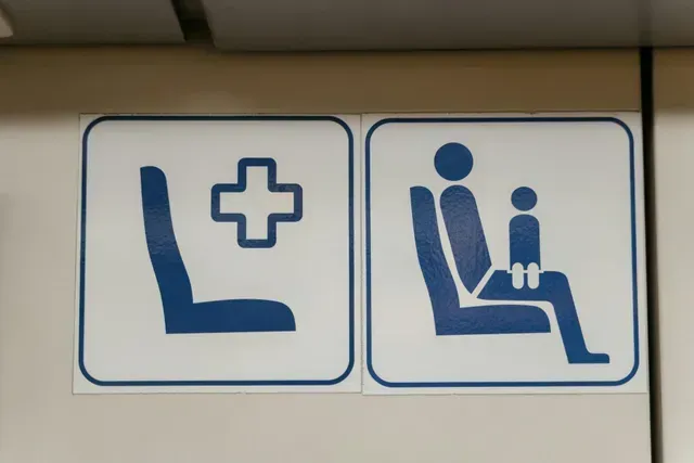 Placas indicando: um assento para alguém que precisa de assistência médica; um assento para um pai e um filho.