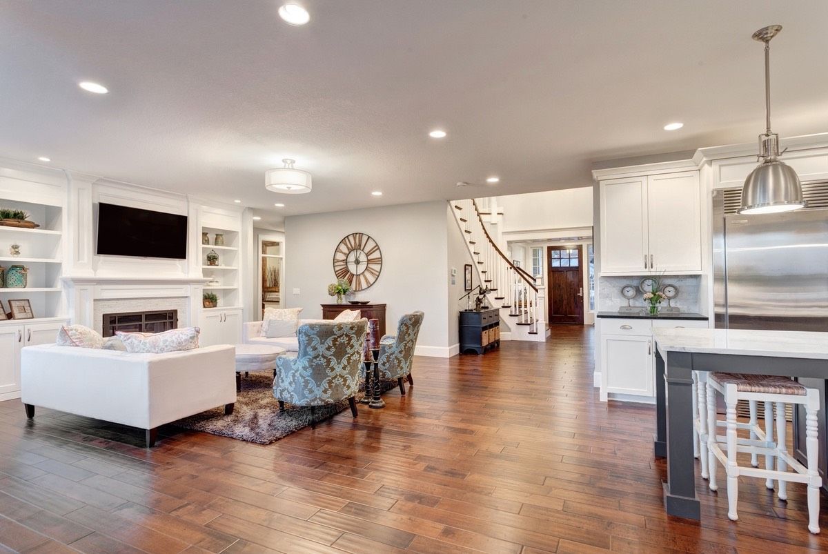 A living room and kitchen in a house with hardwood floors. Design Services