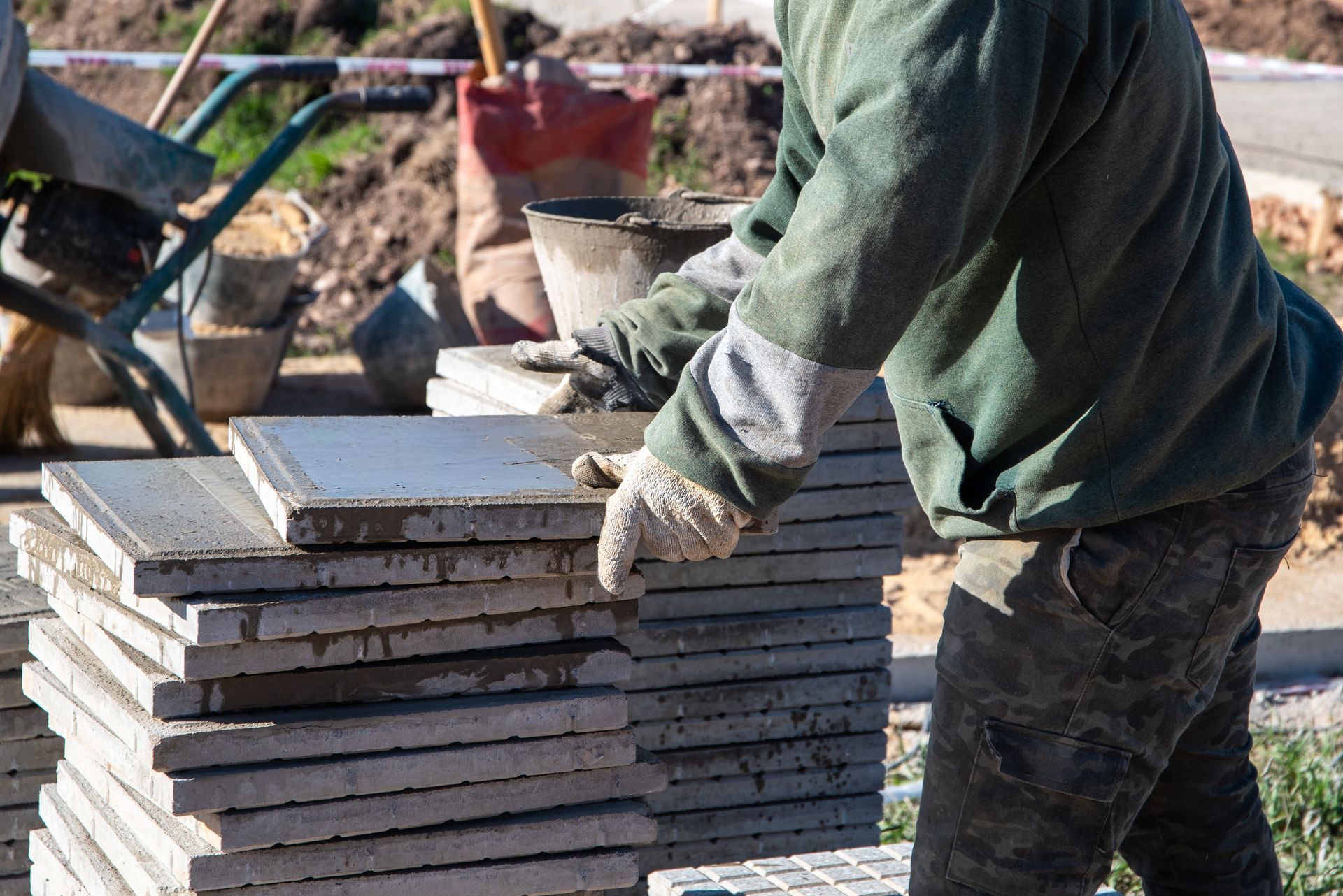 Worker stacking concrete slabs outdoors at a construction site Worker stacking concrete slabs outdoors at a construction site