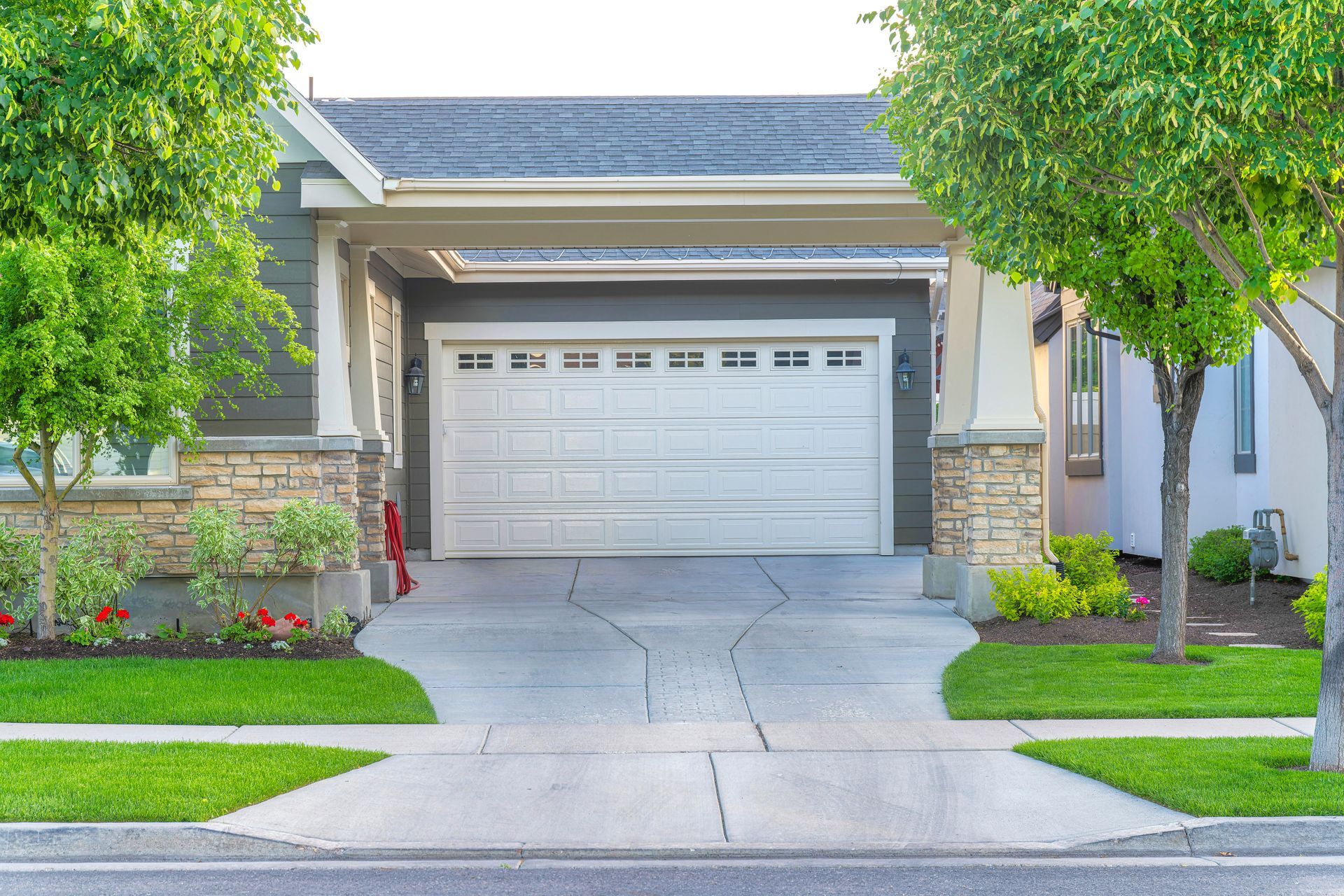 Garage of a house with a concrete driveway intersecting with the sidewalk. Garage of a house with a concrete driveway intersecting with the sidewalk.