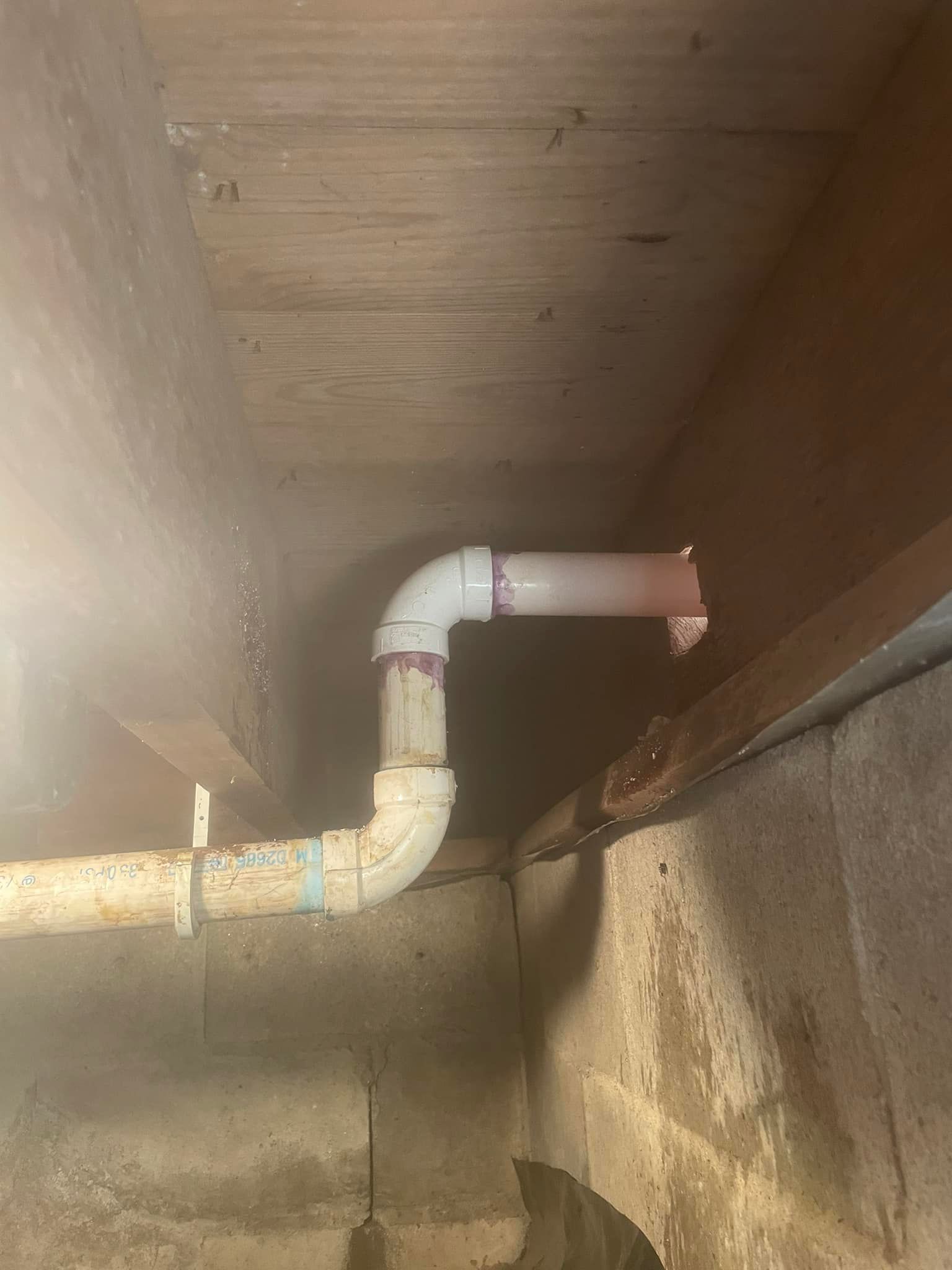 A white pipe is hanging from the ceiling of a room.