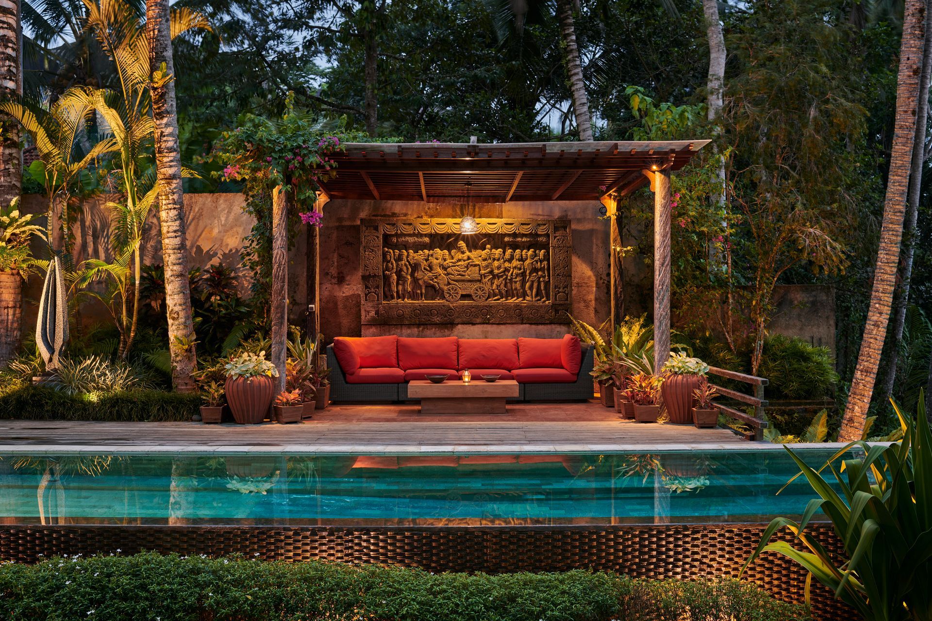 A patio with a couch and a swimming pool in the background