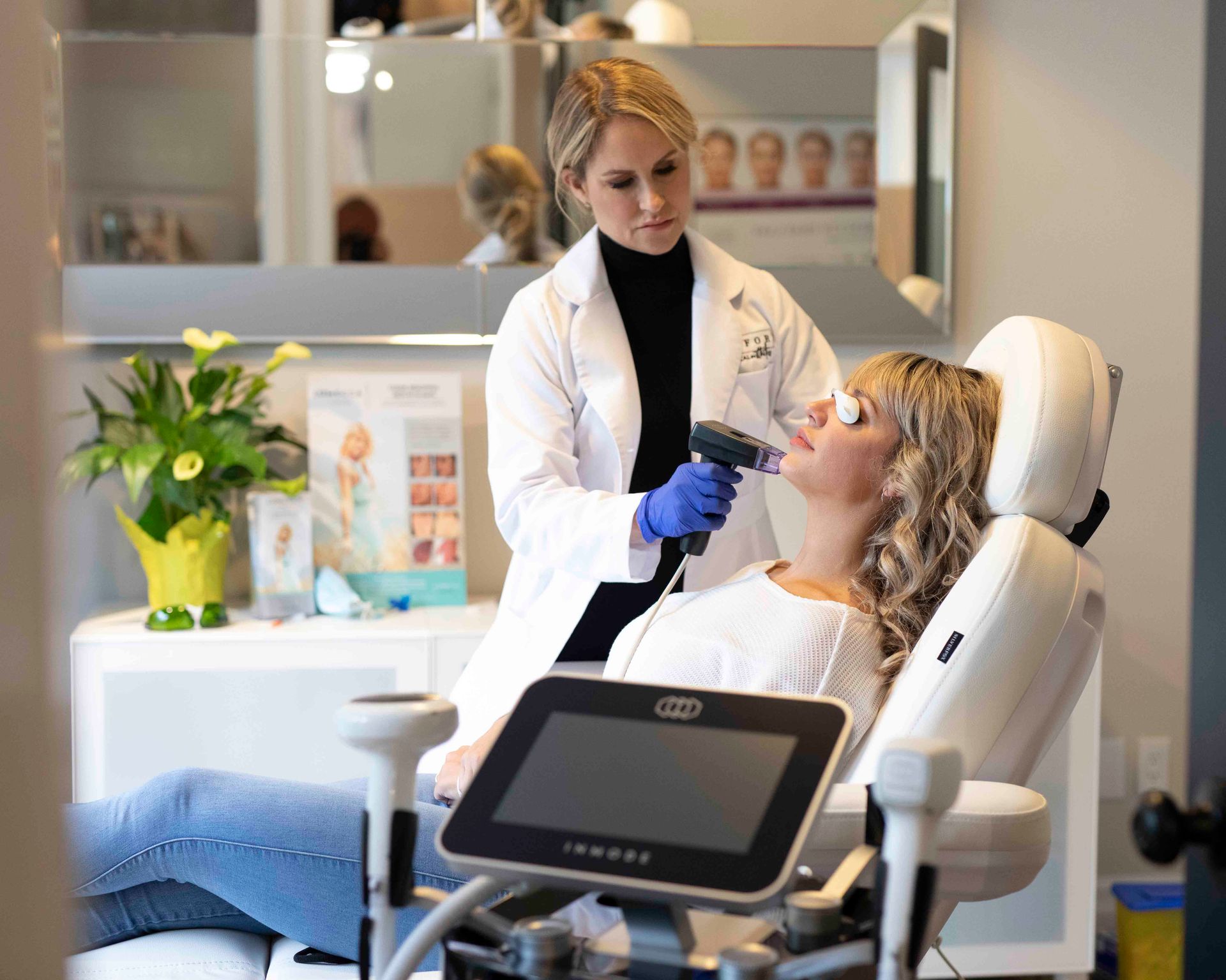 A woman is sitting in a chair getting a treatment from a doctor.