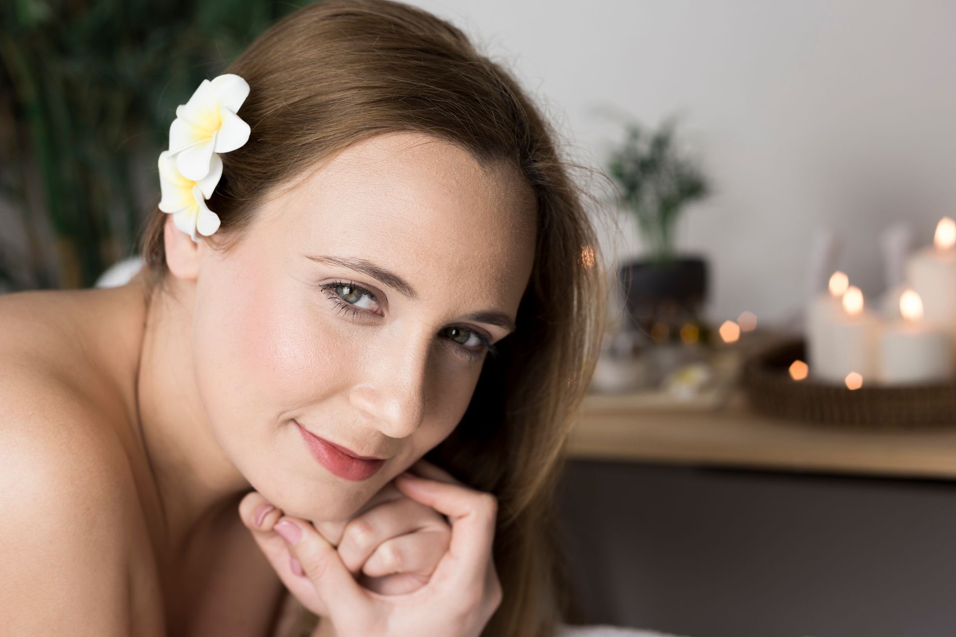 A woman with a flower in her hair is smiling at the camera.