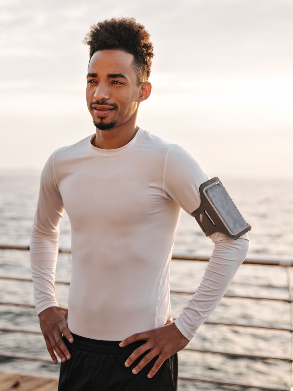 A man is standing on a pier with his hands on his hips.