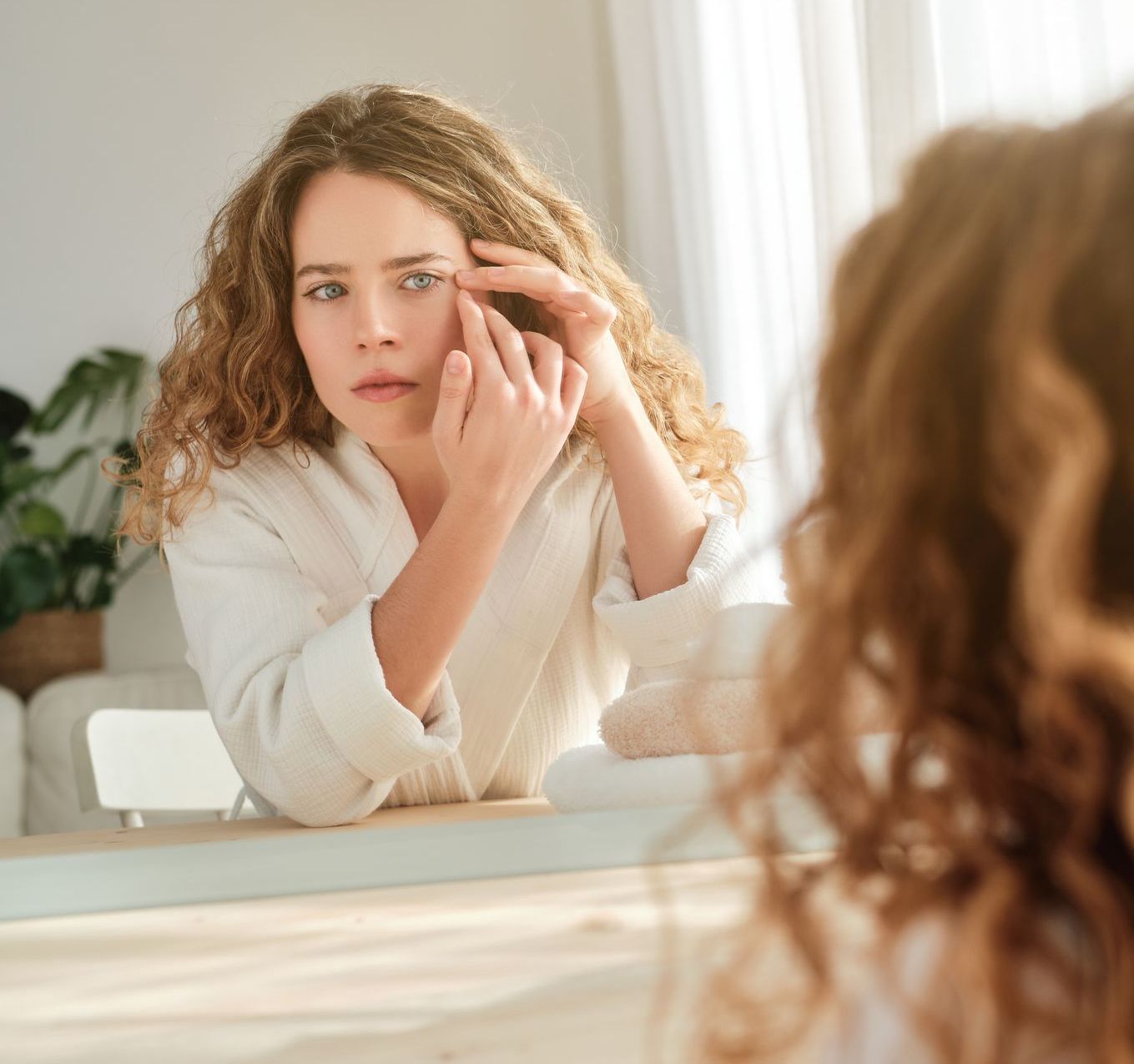 woman looking at wrinkles in mirror