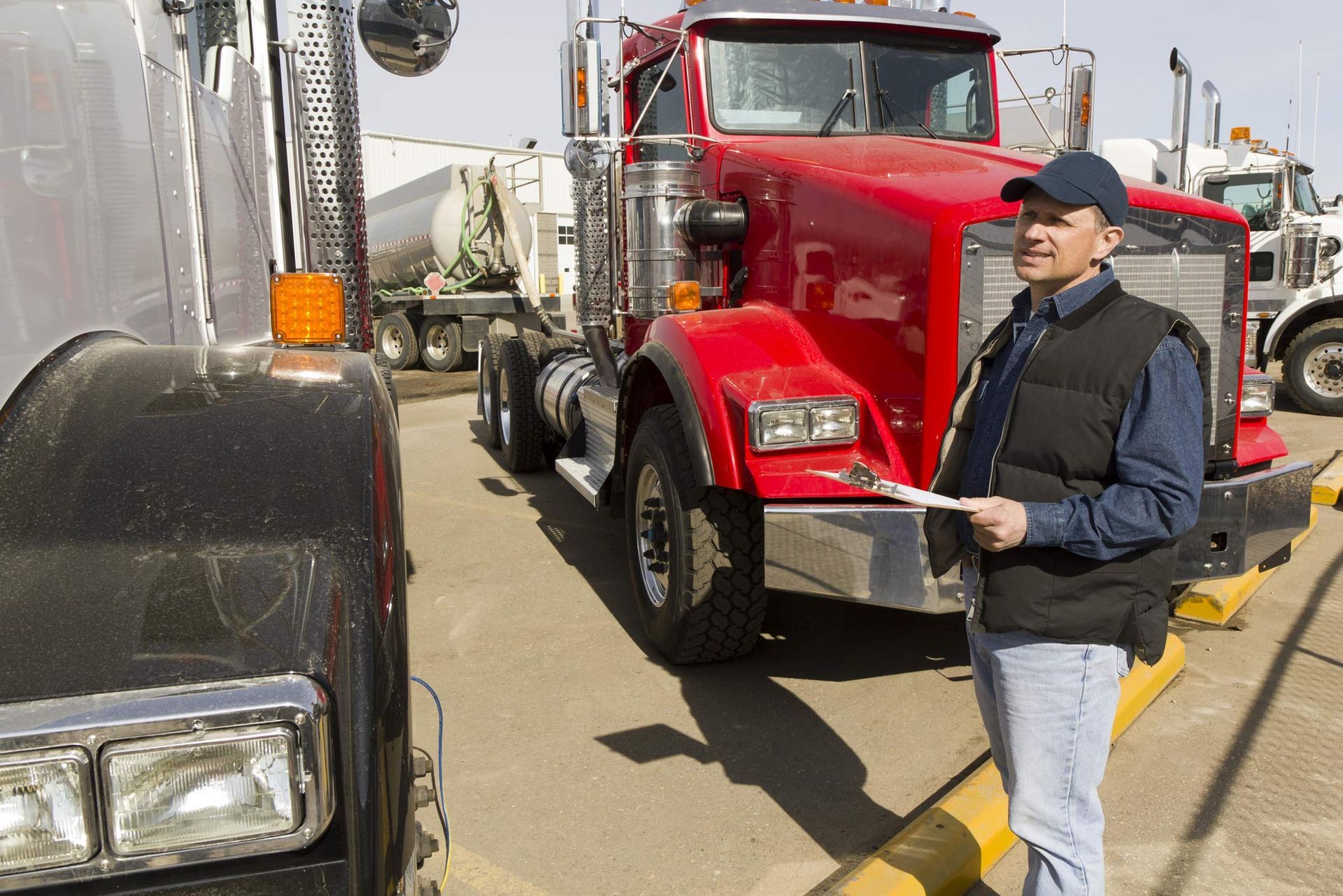 A man is standing in front of a red truck that says kenworth