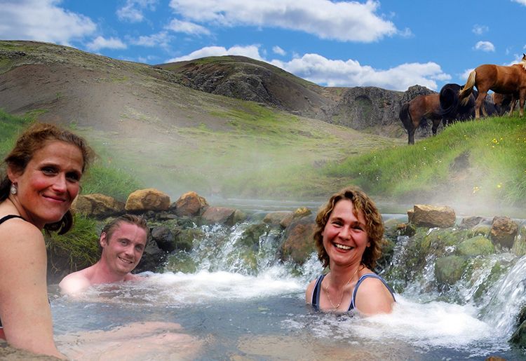 People relaxing in a steaming hot spring with mountains and horses in the background