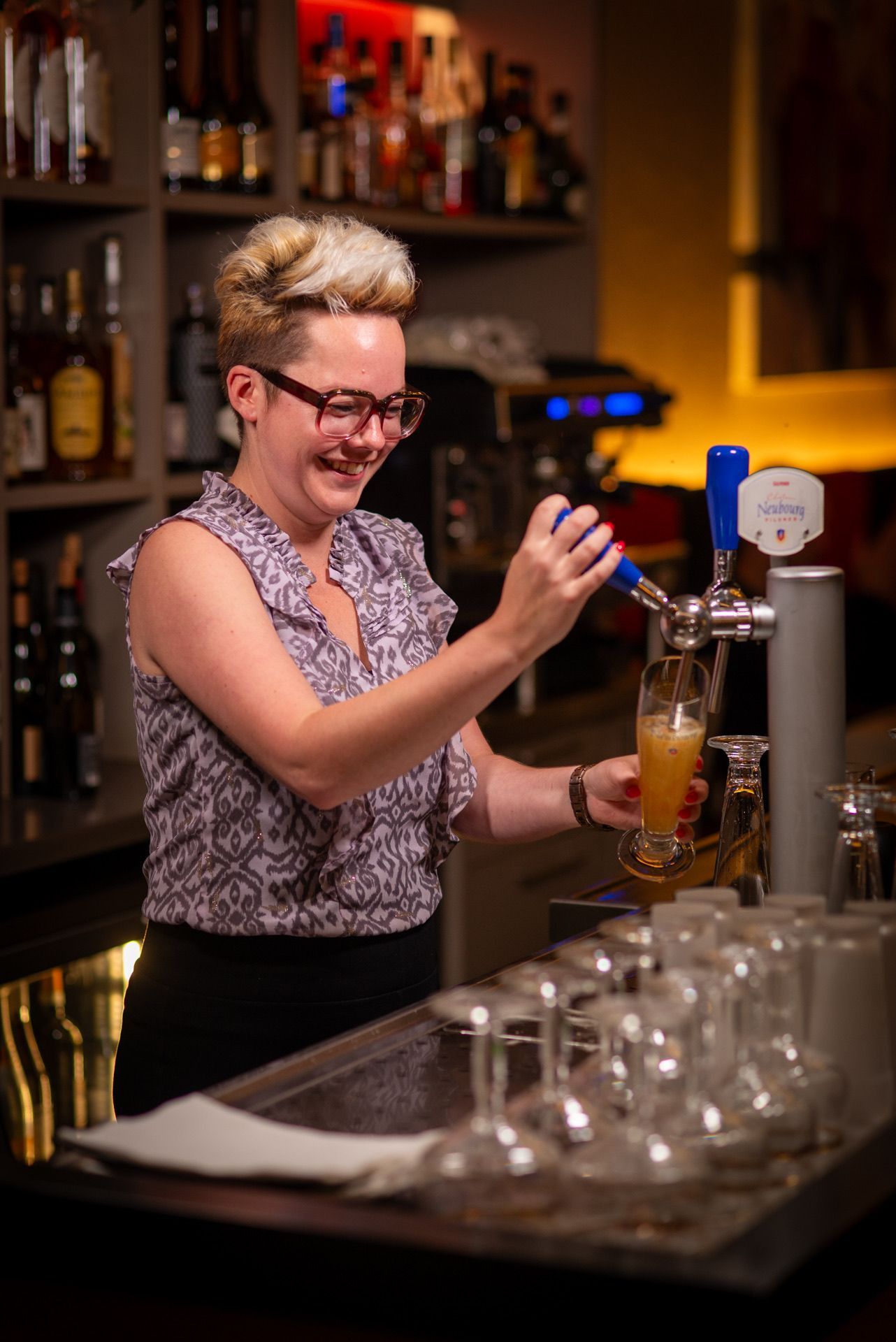 Barman die bier inschenkt, glimlachend, achter de bar.