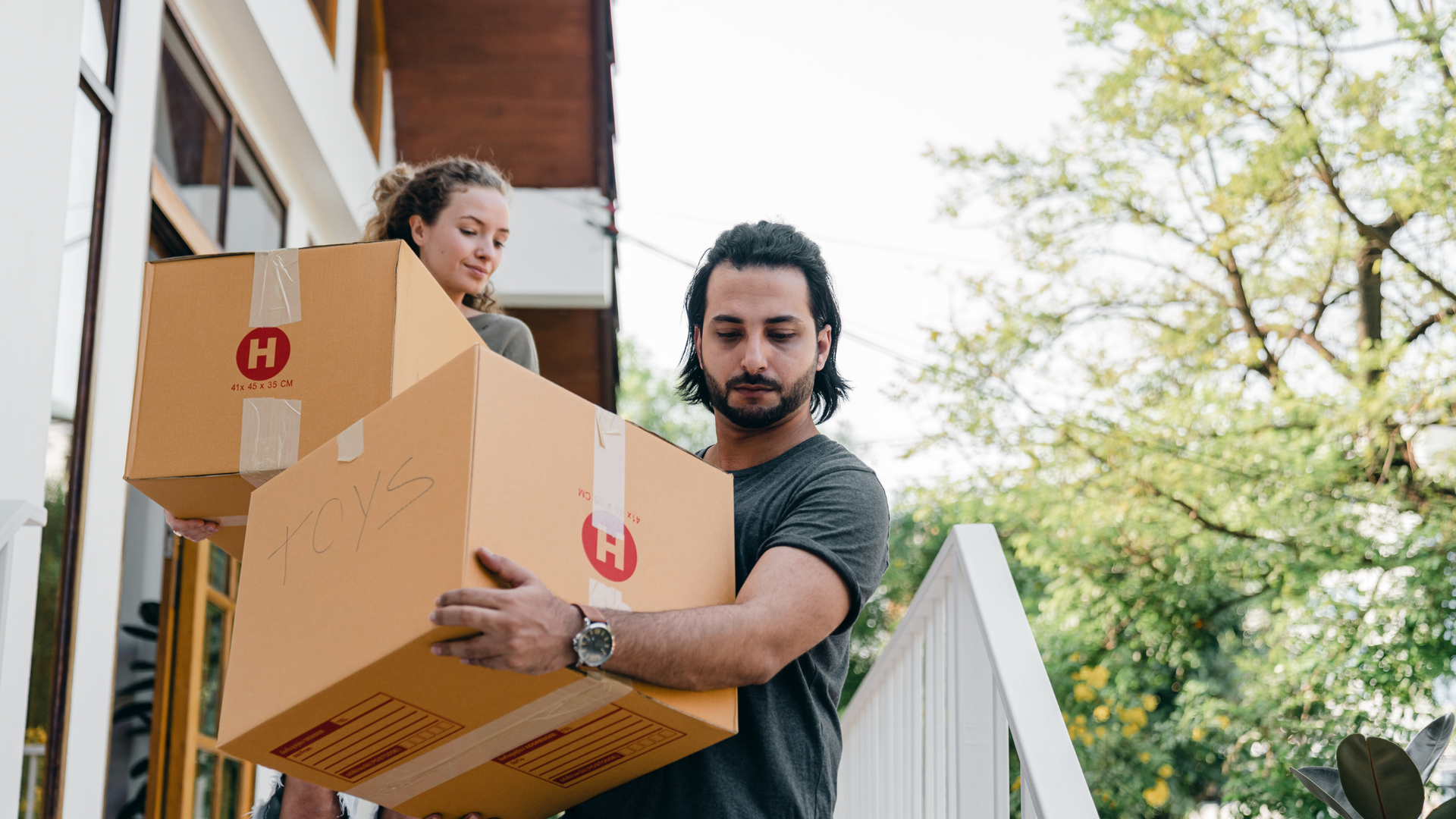 A man and a woman holding boxes, going down the stairs.