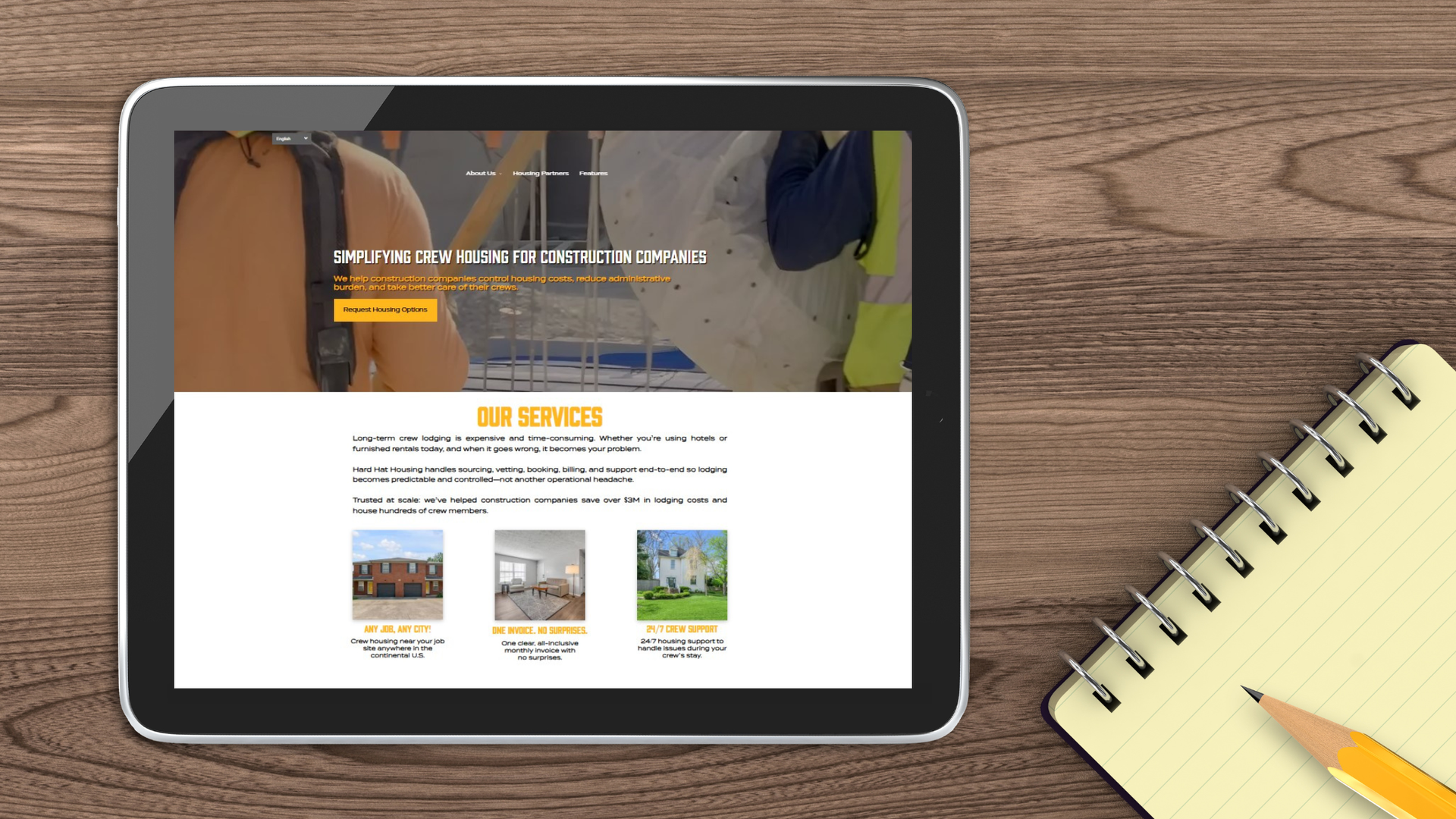 The Hard Hat Housing website open on a tablet, with a pencil and notebook on the table nearby