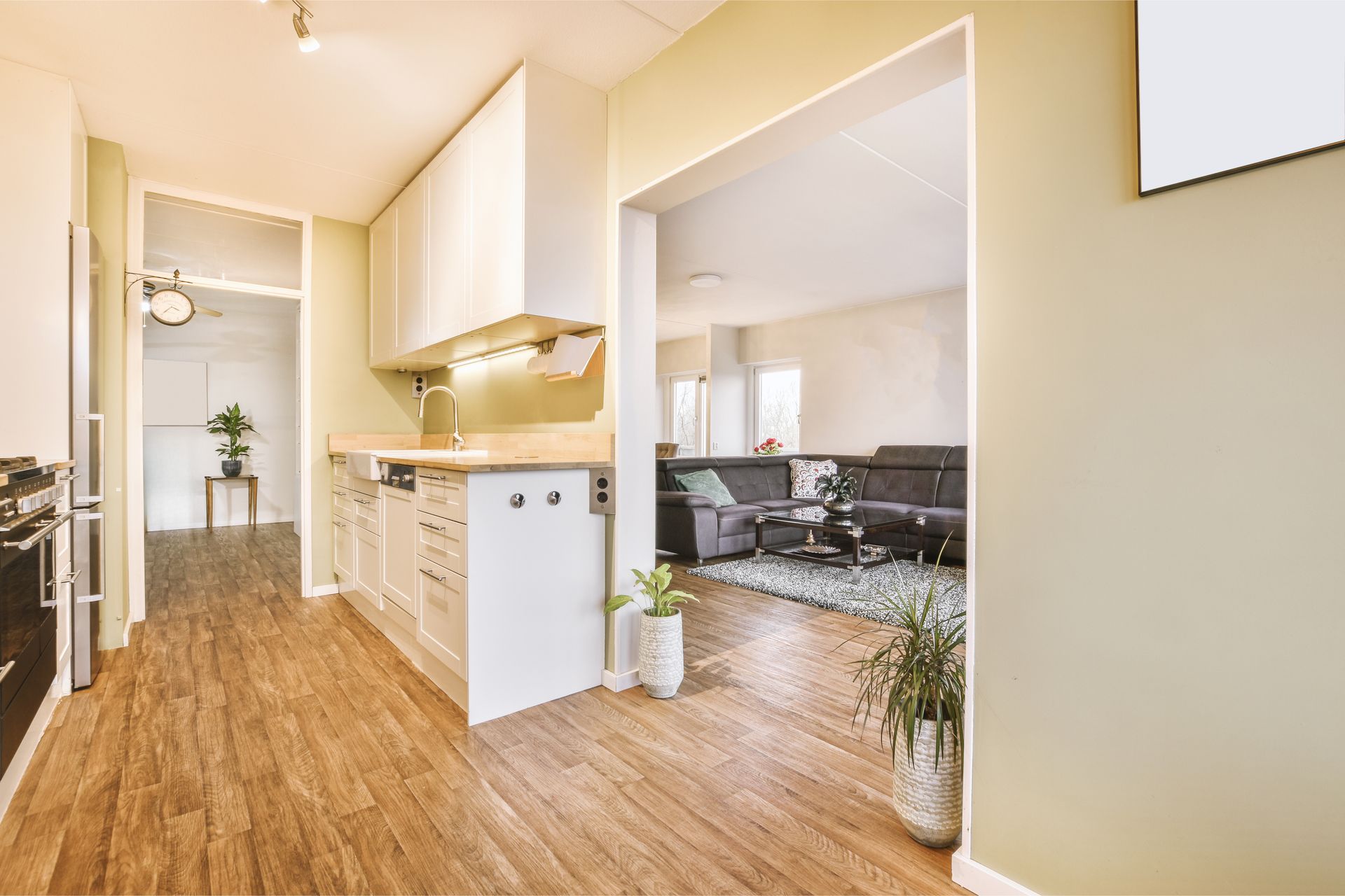A kitchen with wooden floors and white cabinets is open to a living room.