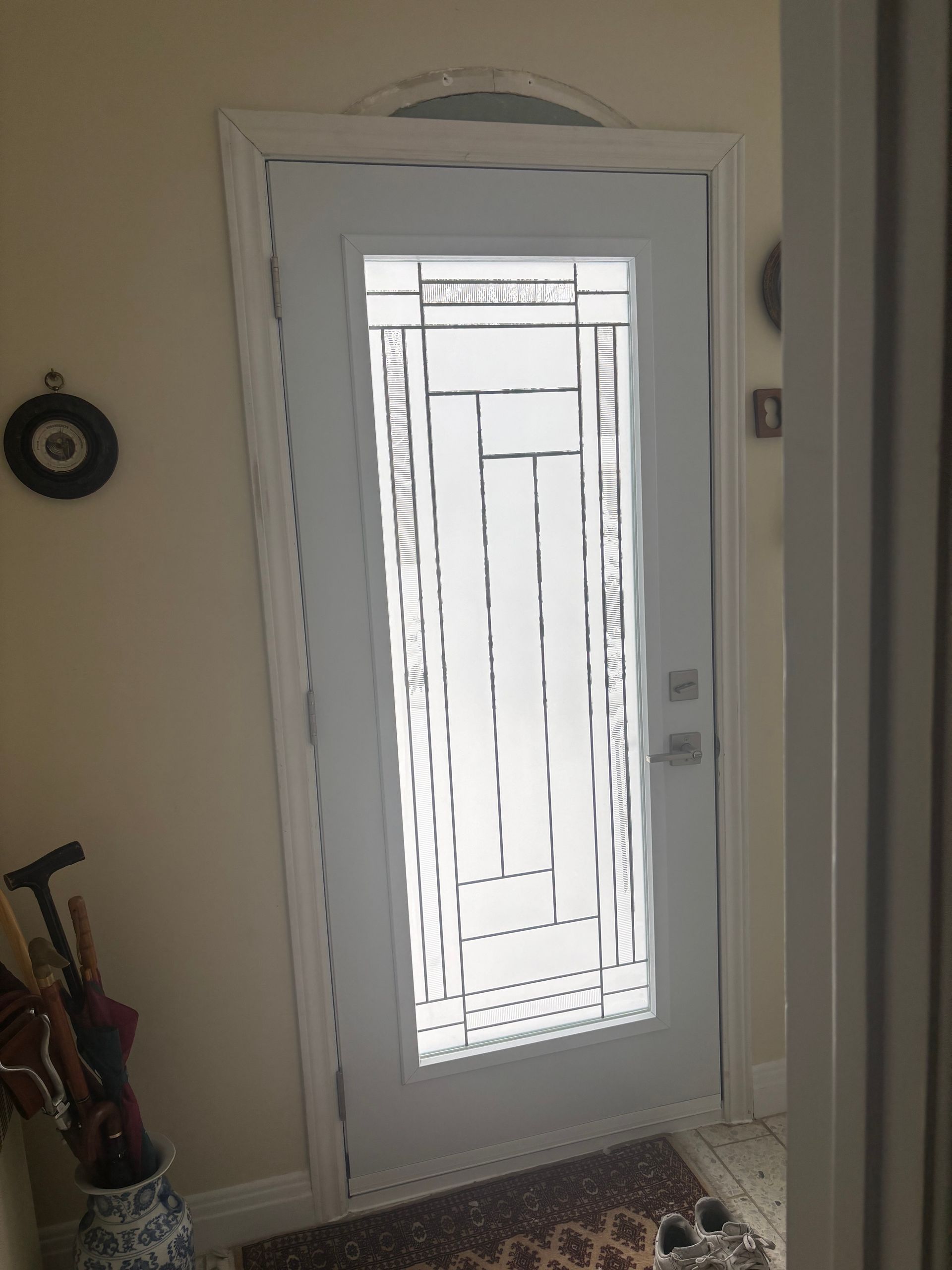 Porte blanche avec panneaux de verre dépoli, moulures cintrées et tapis à motifs.