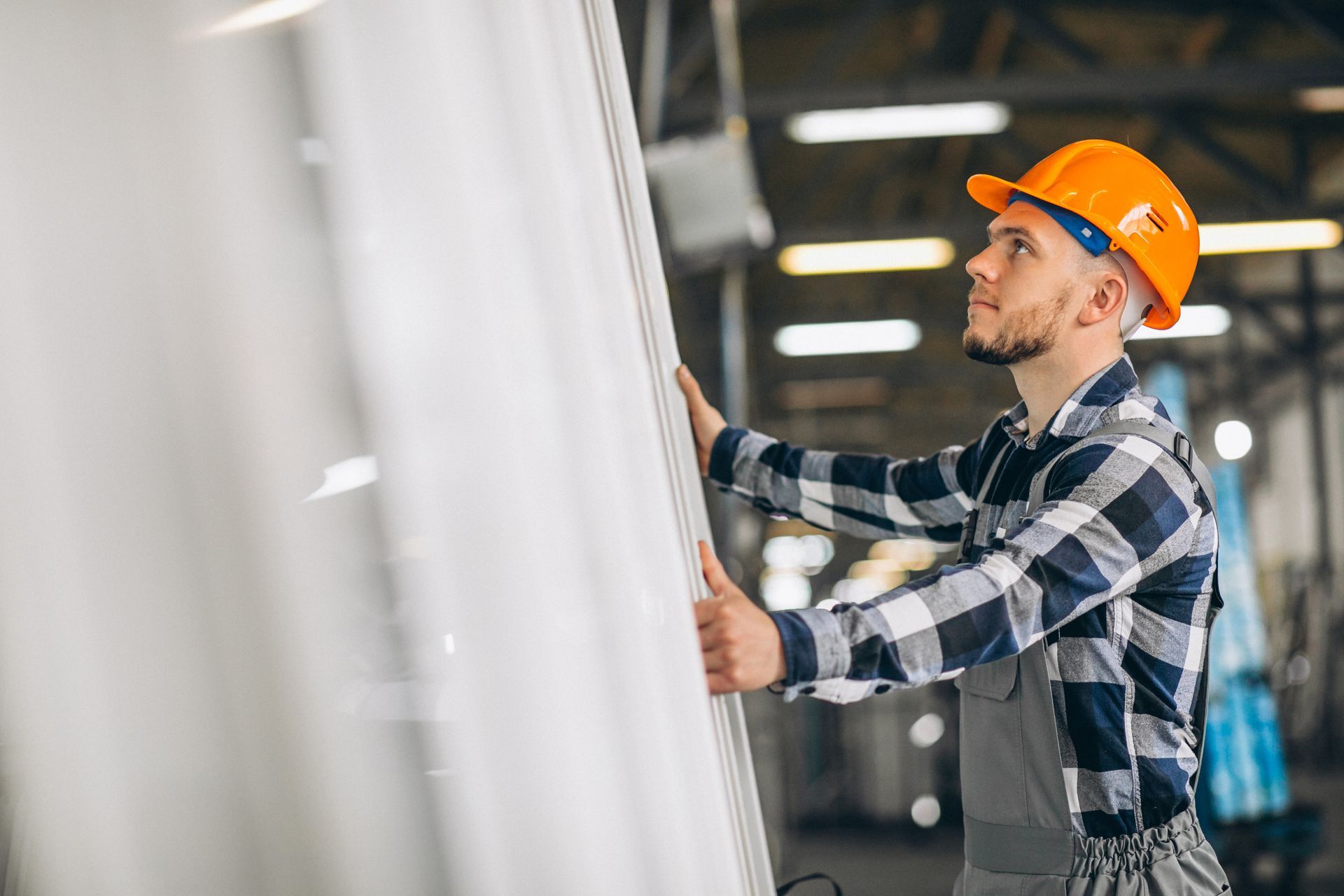 Un homme portant un casque tient un morceau de métal dans une usine.