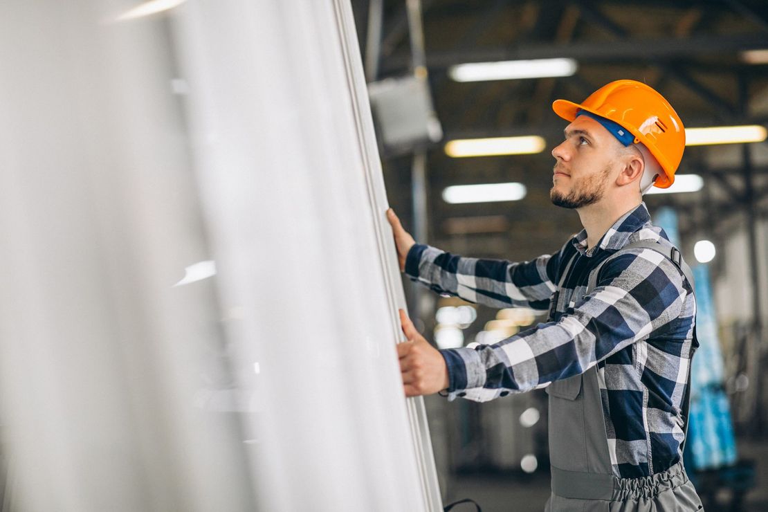 Un homme portant un casque tient un morceau de métal dans une usine.