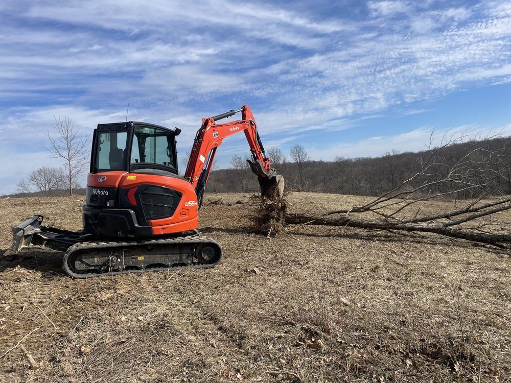 A small orange excavator is digging a hole in a field.