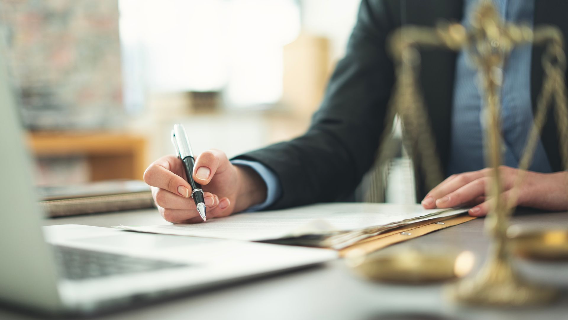 Business lawyer signing a legal document beside the scales of justice
