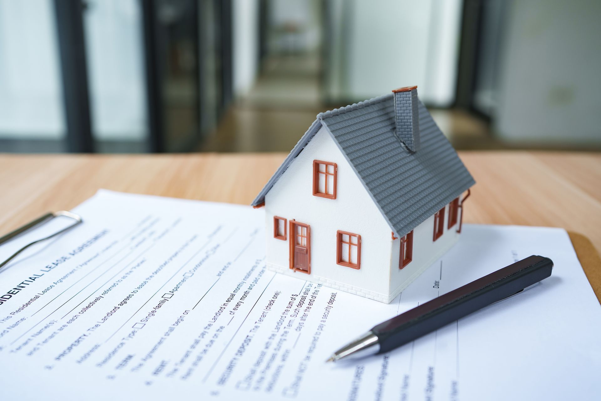 Model house on a real estate contract with a pen on a desk