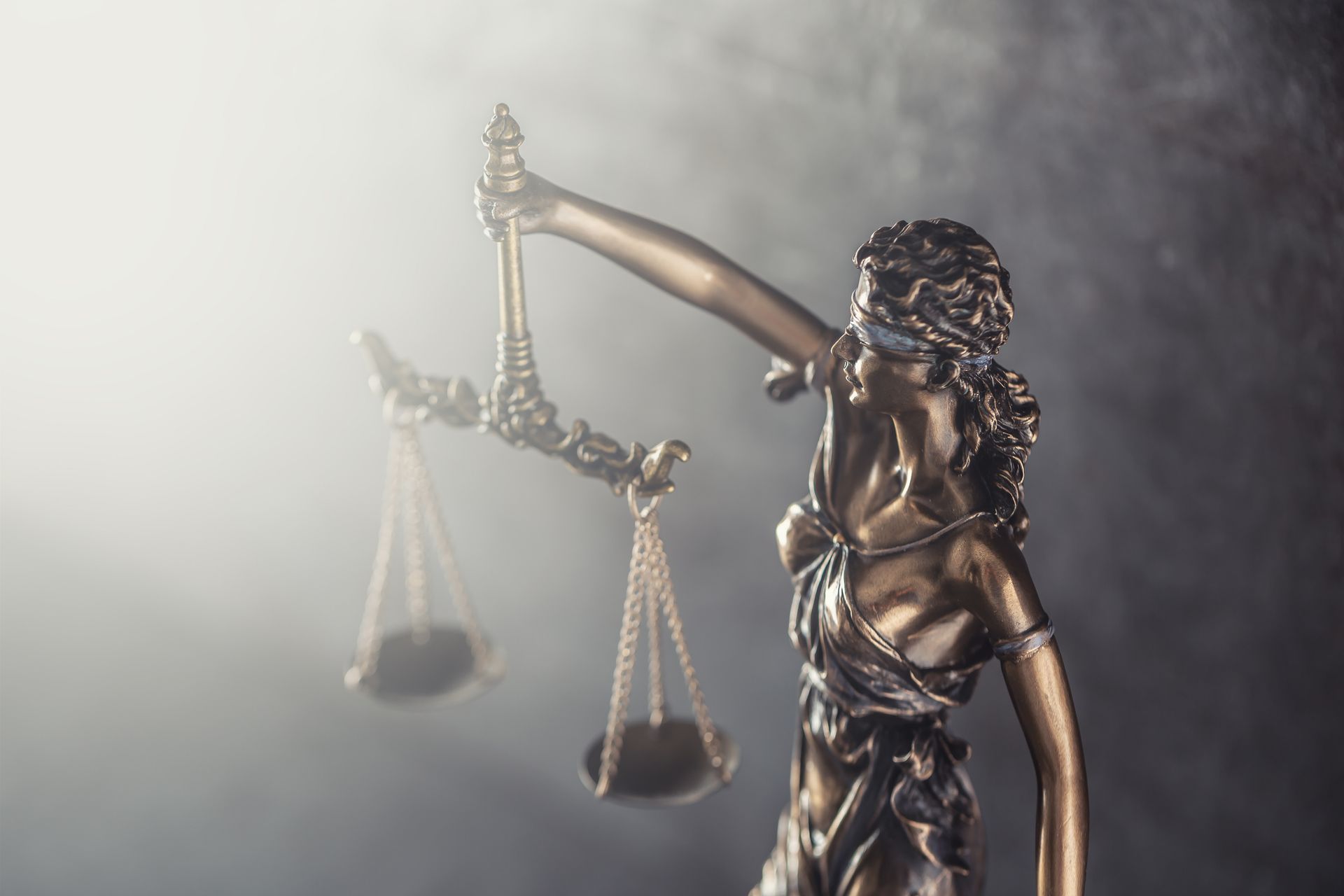 Statue of Lady Justice with blindfold, holding scales, in a smoky atmosphere.