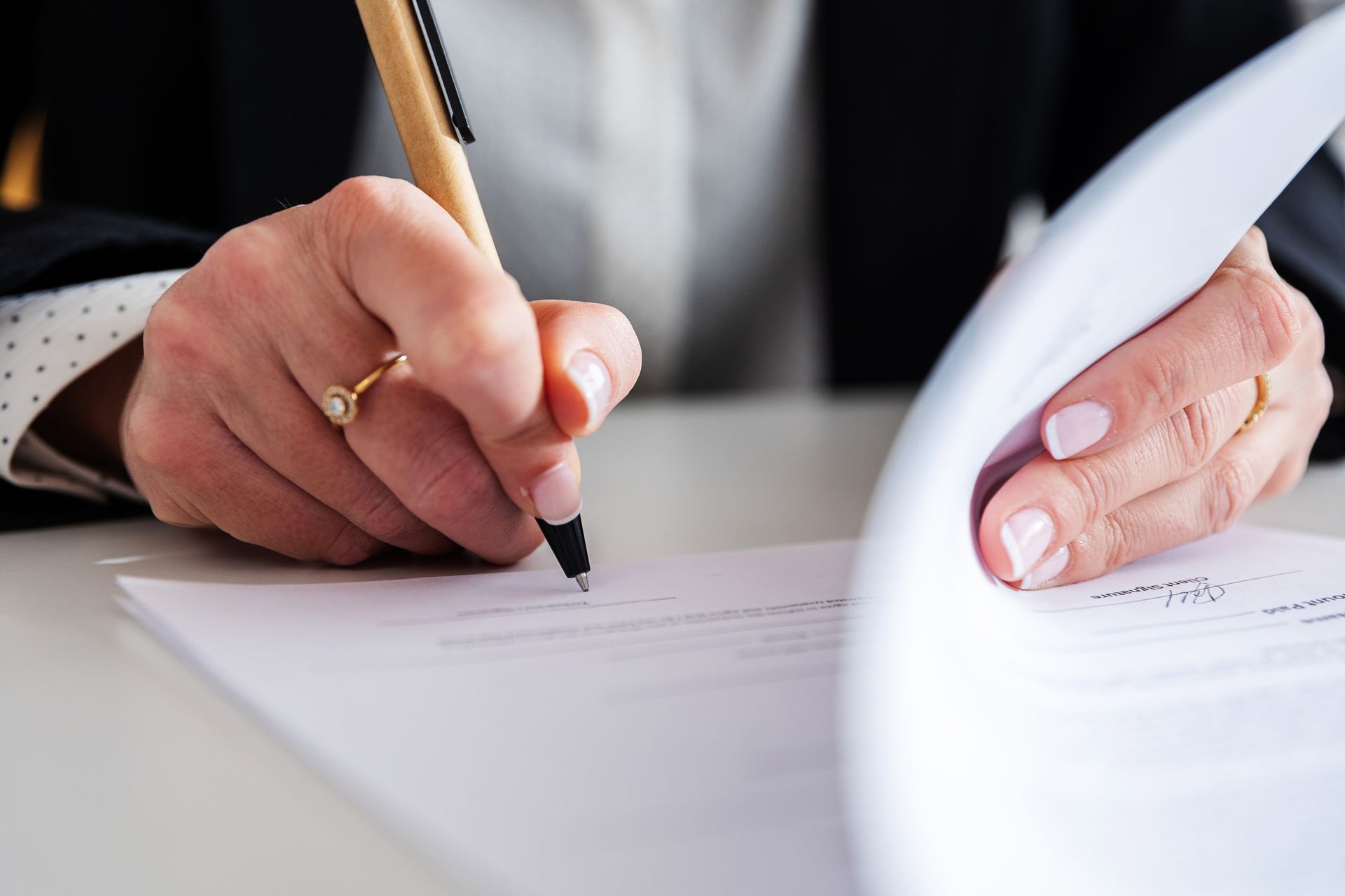 Close-up view of a businesswoman diligently signing a legal document at her office desk.
