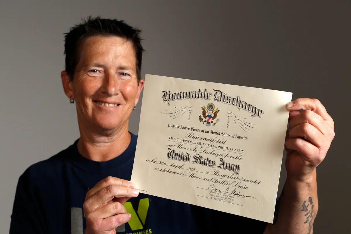 Person smiling and holding up a certificate against a plain gray background