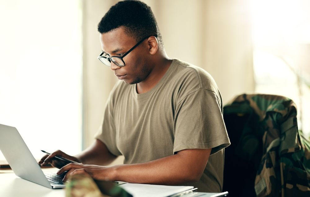 Person working on a laptop at a table in a bright room