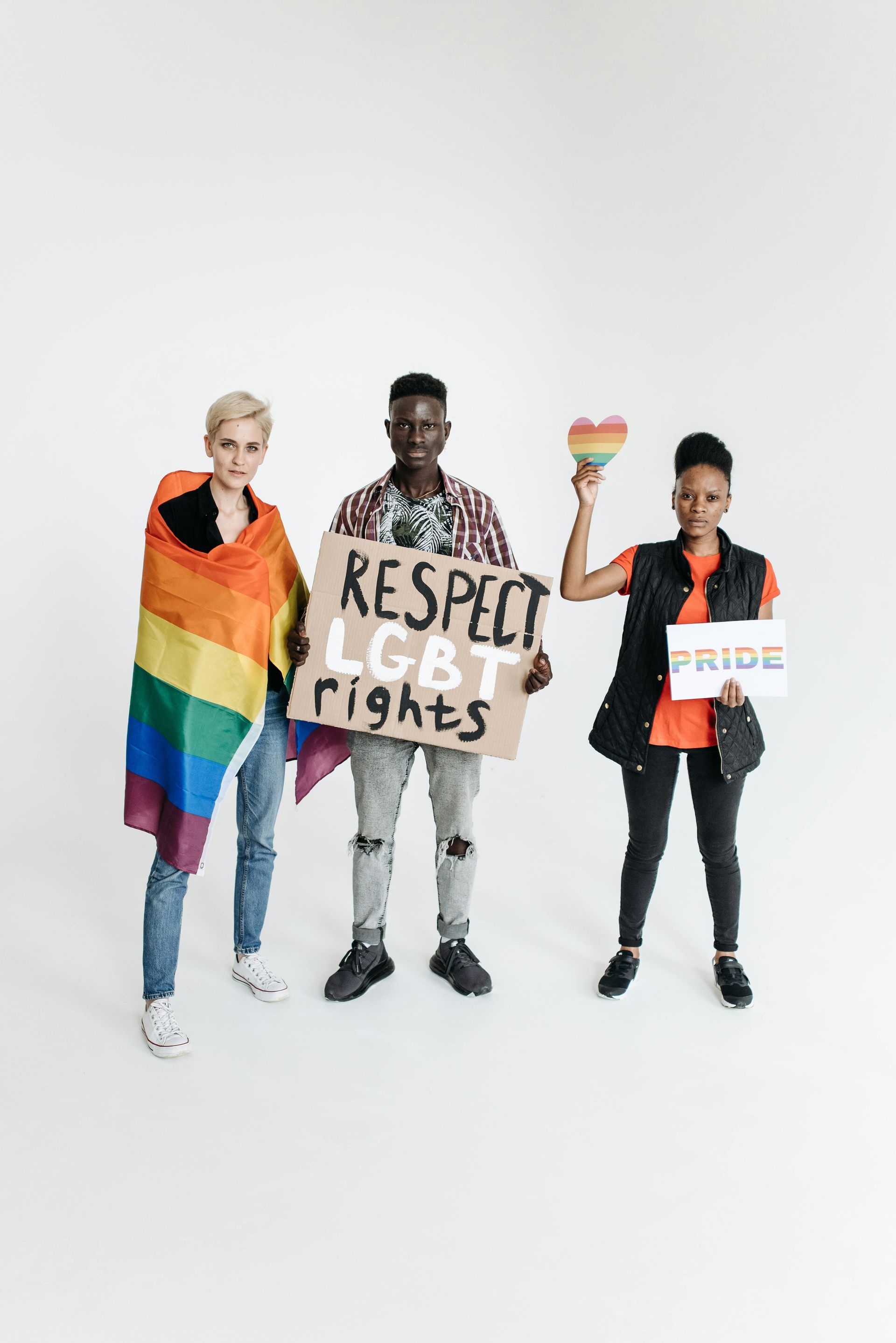 Three people holding rainbow and “Respect LGBTQ+ rights” signs on a white background