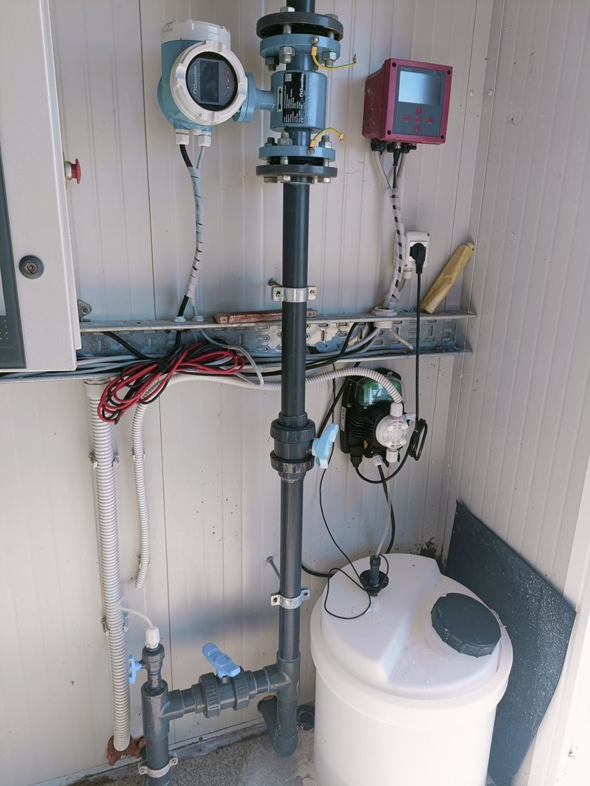 Tecnico in tuta blu e casco protettivo che utilizza un tablet in una sala di trattamento dell'acqua pulita.