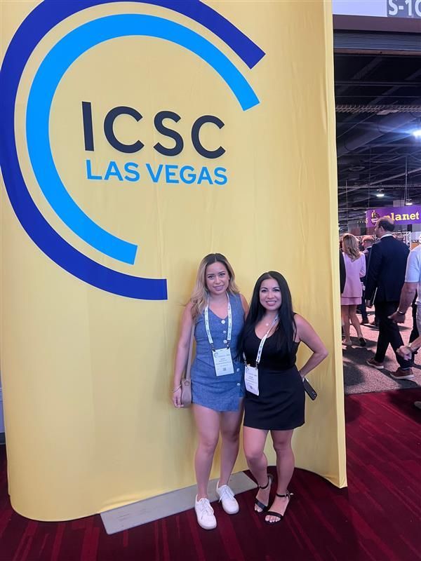 Two women standing in front of a sign that says icsc las vegas