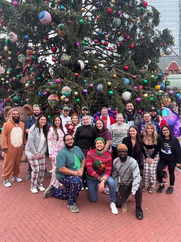 A group of people are posing for a picture in front of a christmas tree.