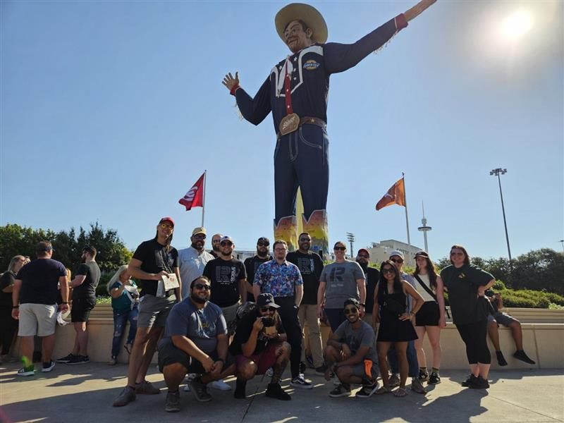 A group of people posing in front of a statue of a cowboy