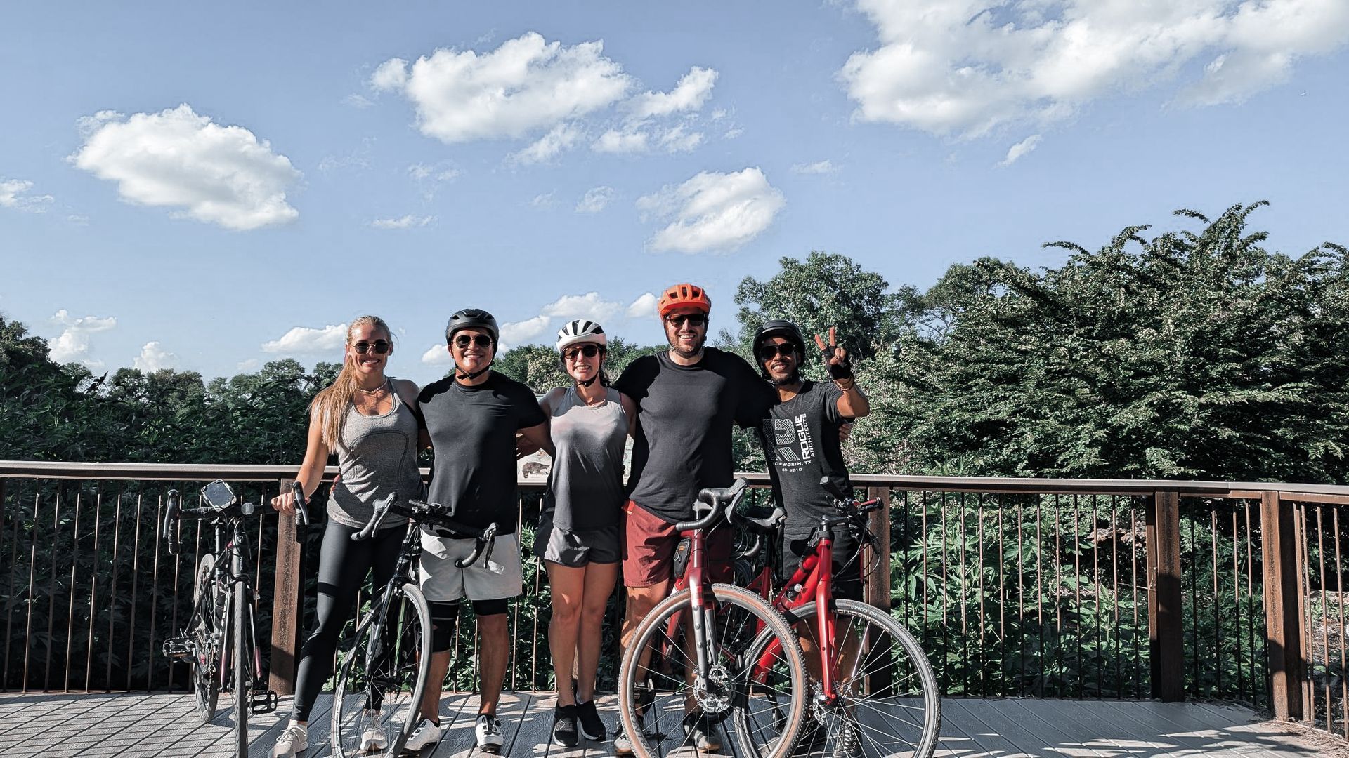 A group of people standing next to bicycles on a bridge.