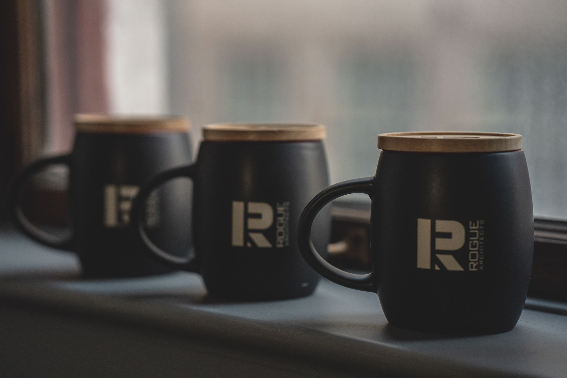 Three rogue coffee mugs are sitting on a window sill