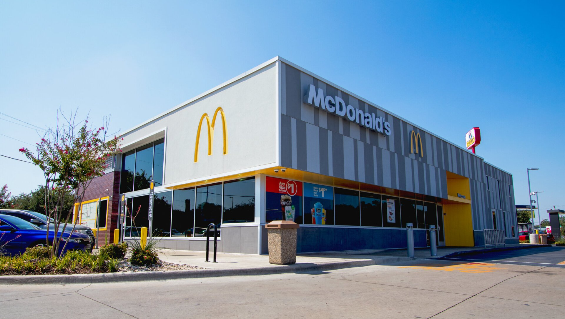 A large mcdonald 's restaurant with a parking lot in front of it.