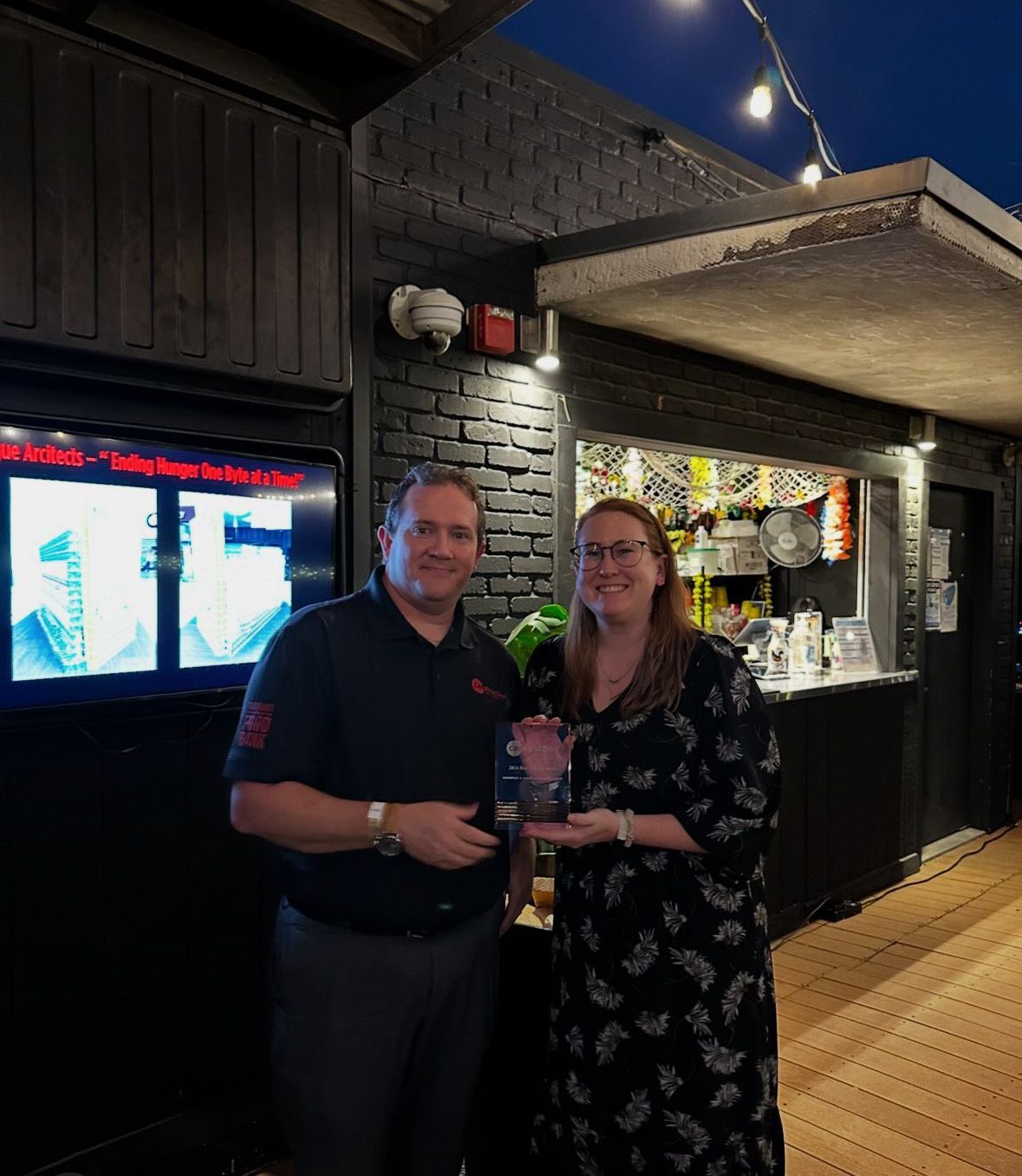 A man and a woman are standing next to each other holding a trophy.