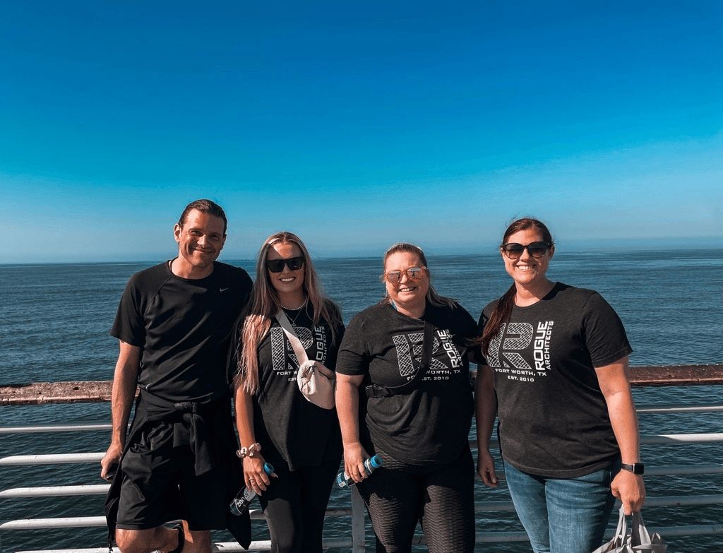 A group of people are standing next to each other on a pier overlooking the ocean.
