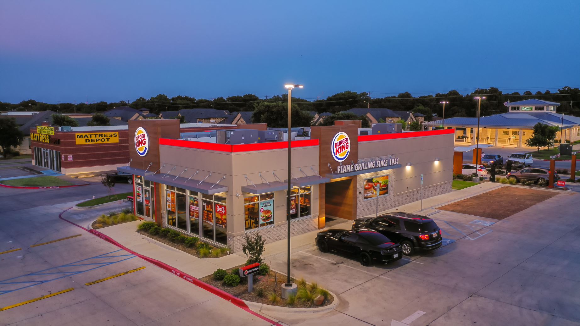 An aerial view of a burger king restaurant with cars parked in front of it.