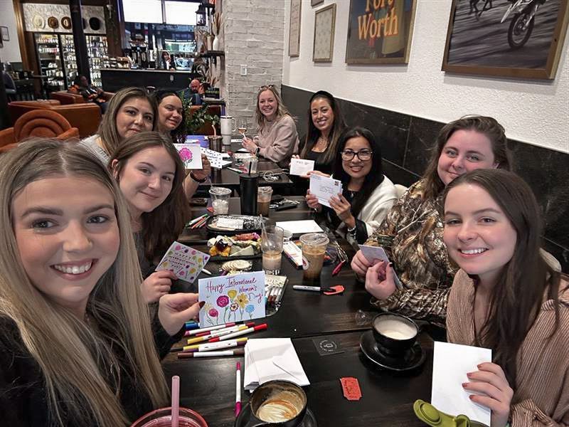 A group of women are sitting at a table in a restaurant holding cards.
