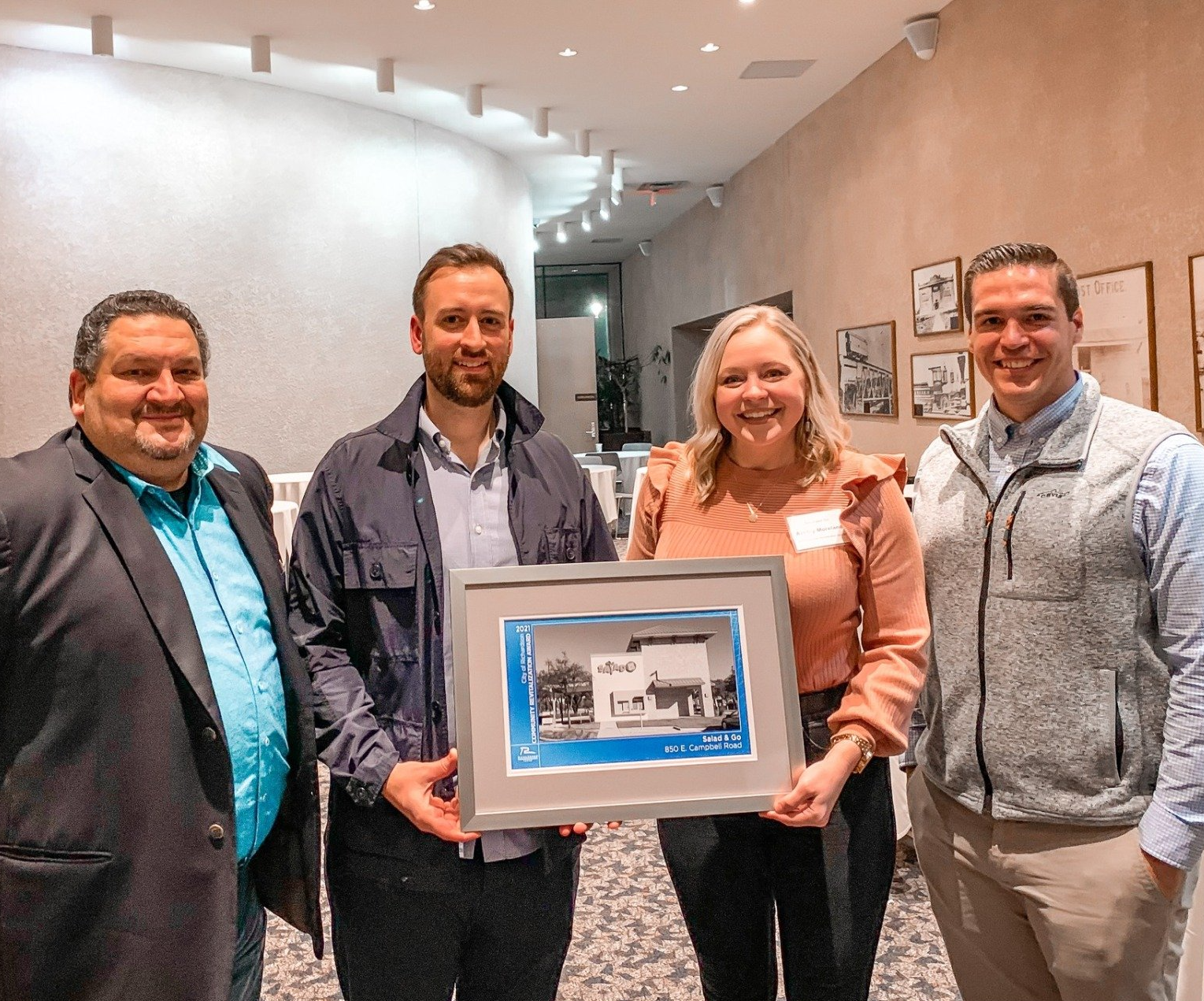 A group of people are standing next to each other holding a framed picture.