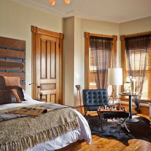 A bedroom with a bed , chair , table , and chess board.